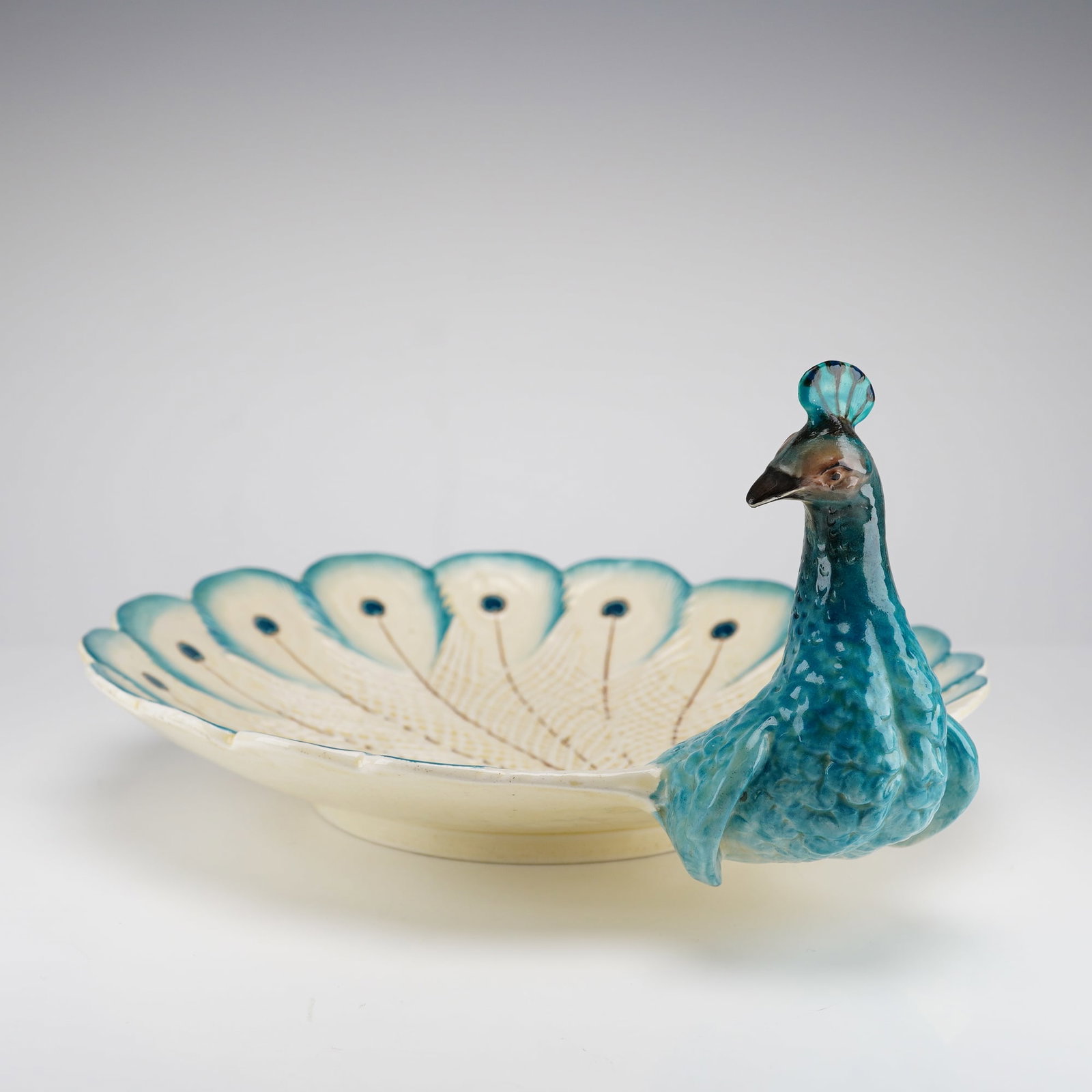 Wedgwood Majolica Peacock Dish: A Victorian-era majolica glazed earthenware dish produced by the English firm Wedgwood, featuring a sculptural peacock motif. The vessel is modeled with the bird head and neck in full relief at one ed