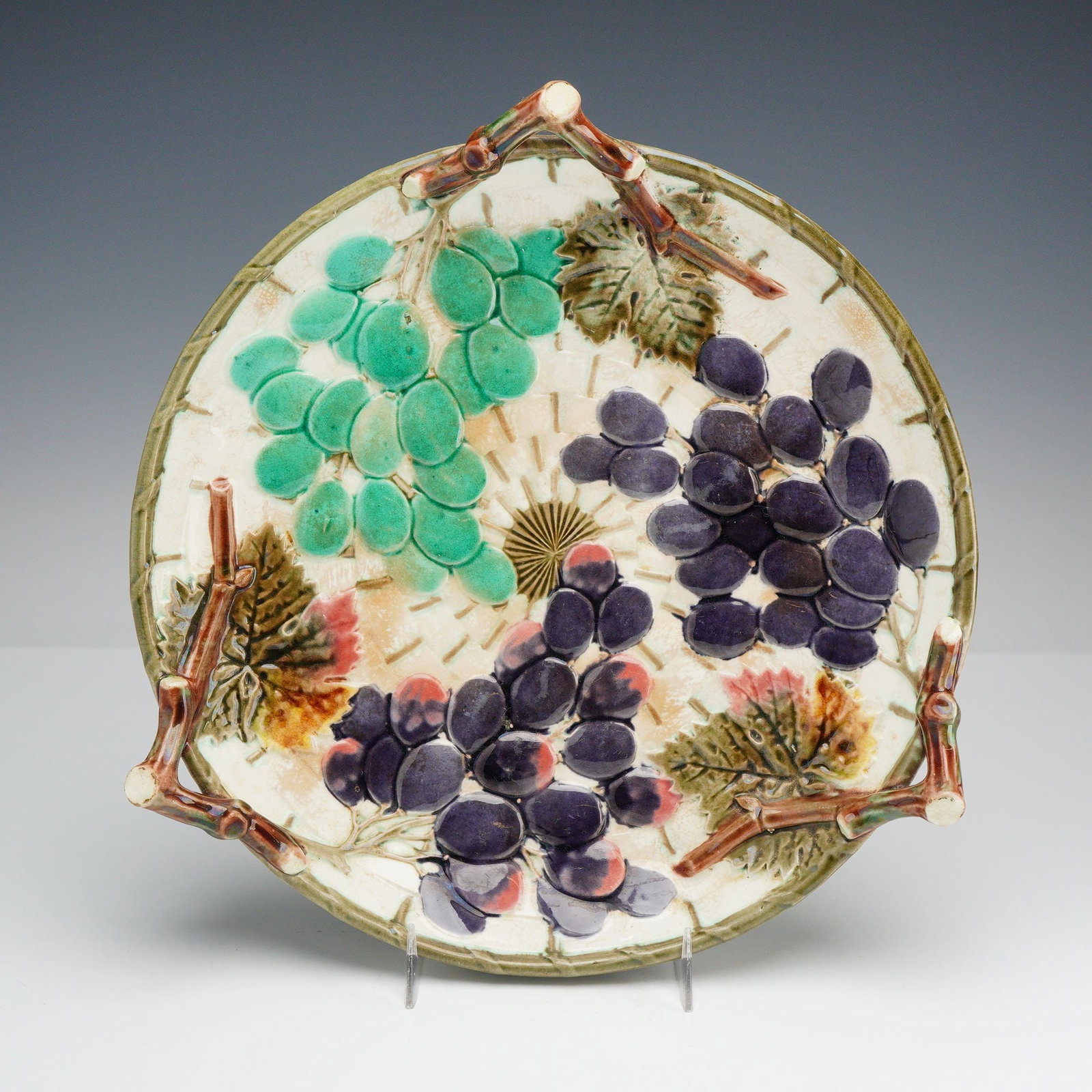 Wedgwood Majolica Grape and Vine Leaf Tripod Dish: A late 19th-century majolica earthenware dish manufactured by the English firm Wedgwood. The circular form is relief-molded with three clusters of grapes in turquoise-green and deep purple glazes, set
