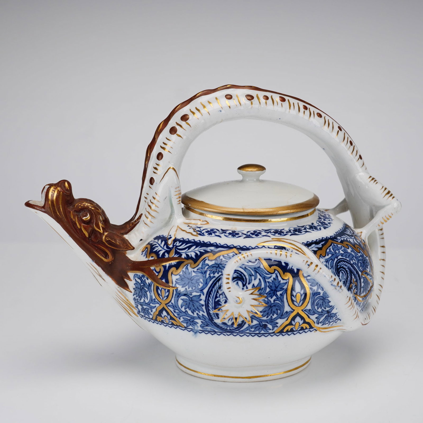 Wedgwood Porcelain Teapot, Indian Pattern: A celebrated Aesthetic Movement design attributed to Christopher Dresser. The teapot is designed with a globular body and distinctive figural elements, including a spout modeled as a dragon's head and
