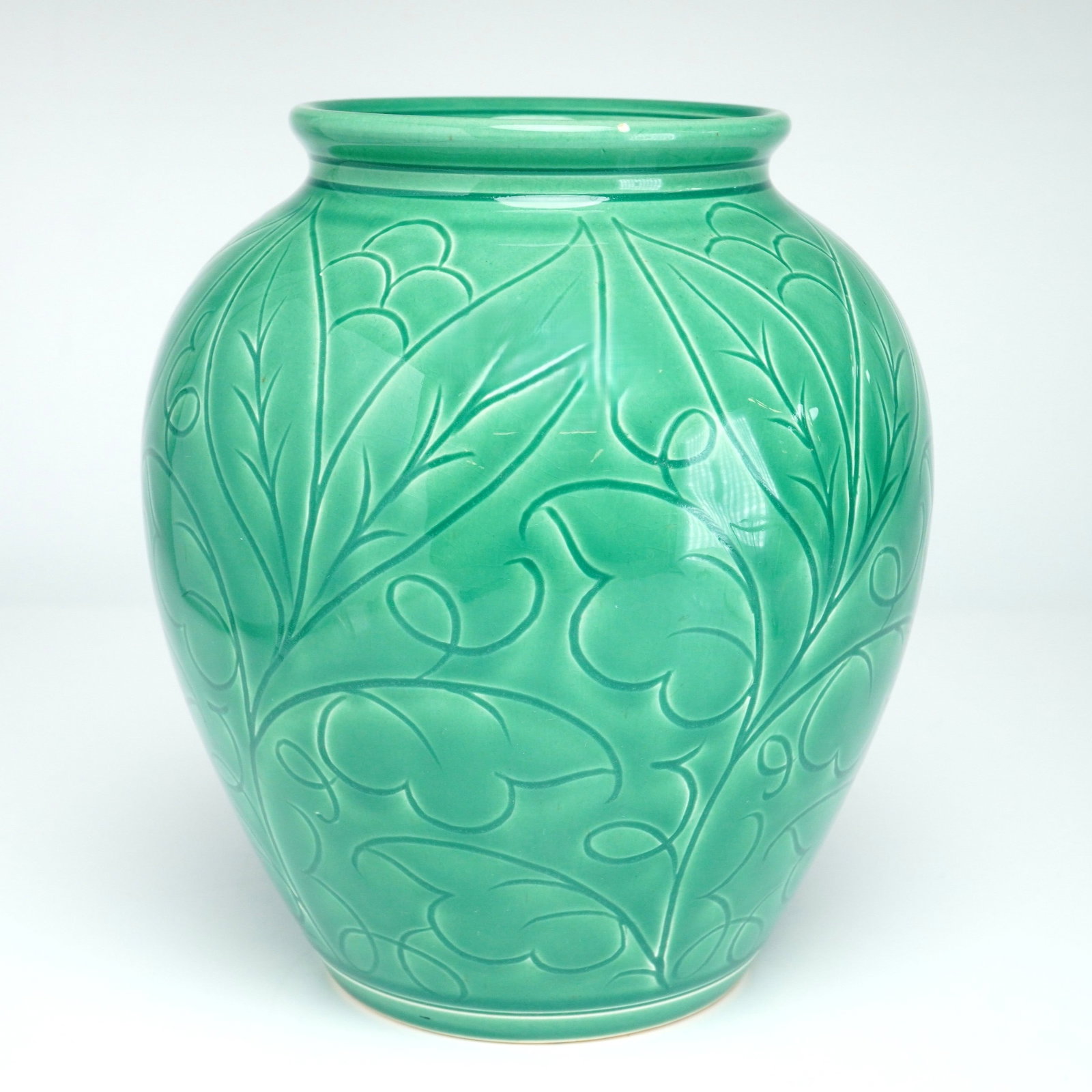 Wedgwood Celadon-Green Glazed Floral and Foliate Motif Vase: This ceramic vase, c. 1935, is crafted from glazed earthenware and features a bulbous ovoid body with a short, flared rim and a narrow-tapered base. The exterior is decorated with a continuous molded 
