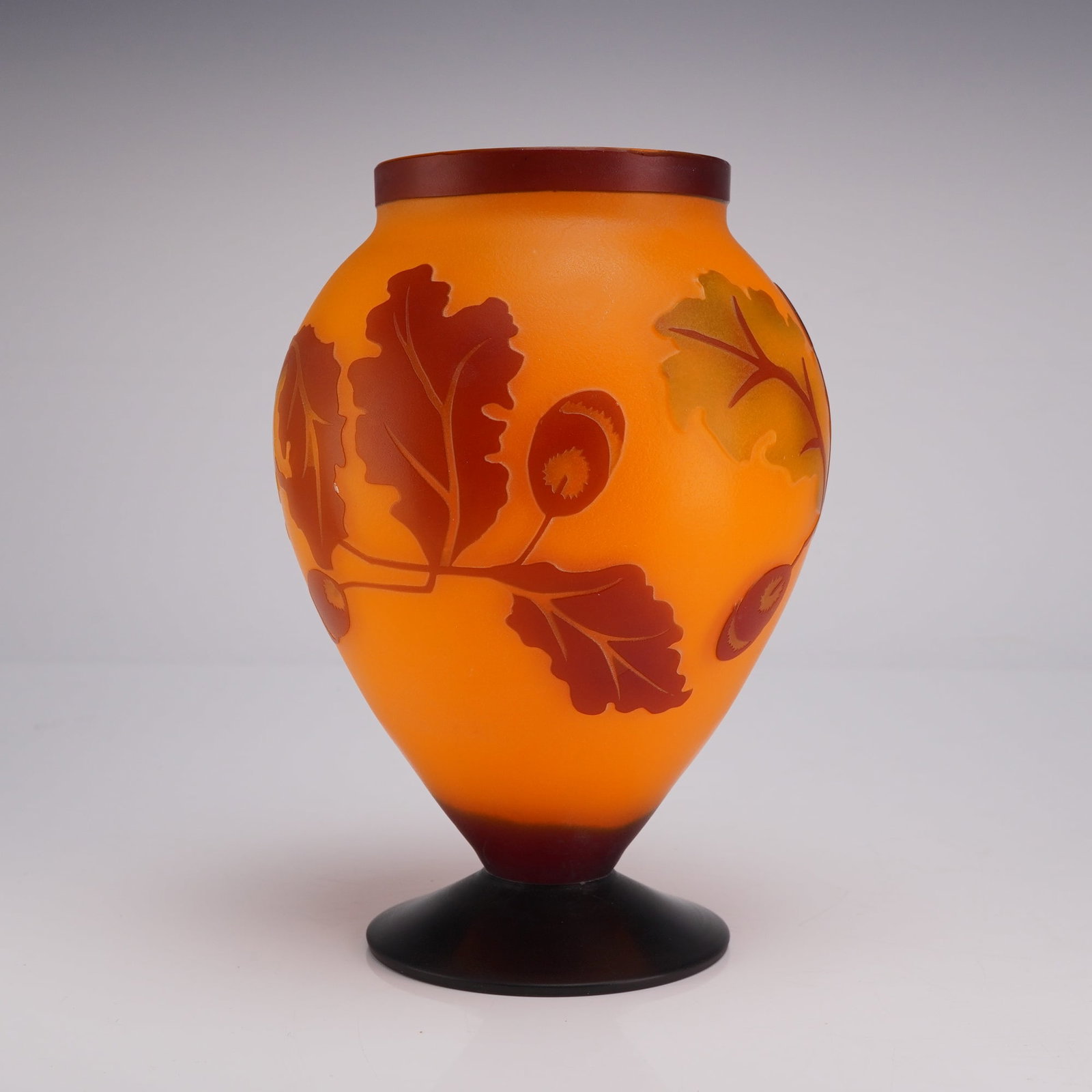Galle Style Cameo Glass Footed Vase with Oak Leaf and Acorn Design: This contemporary cameo glass vase is executed in the Art Nouveau style of Emile Galle. The vessel is constructed of translucent orange and yellow glass with multi-layered overlays in shades of dark r