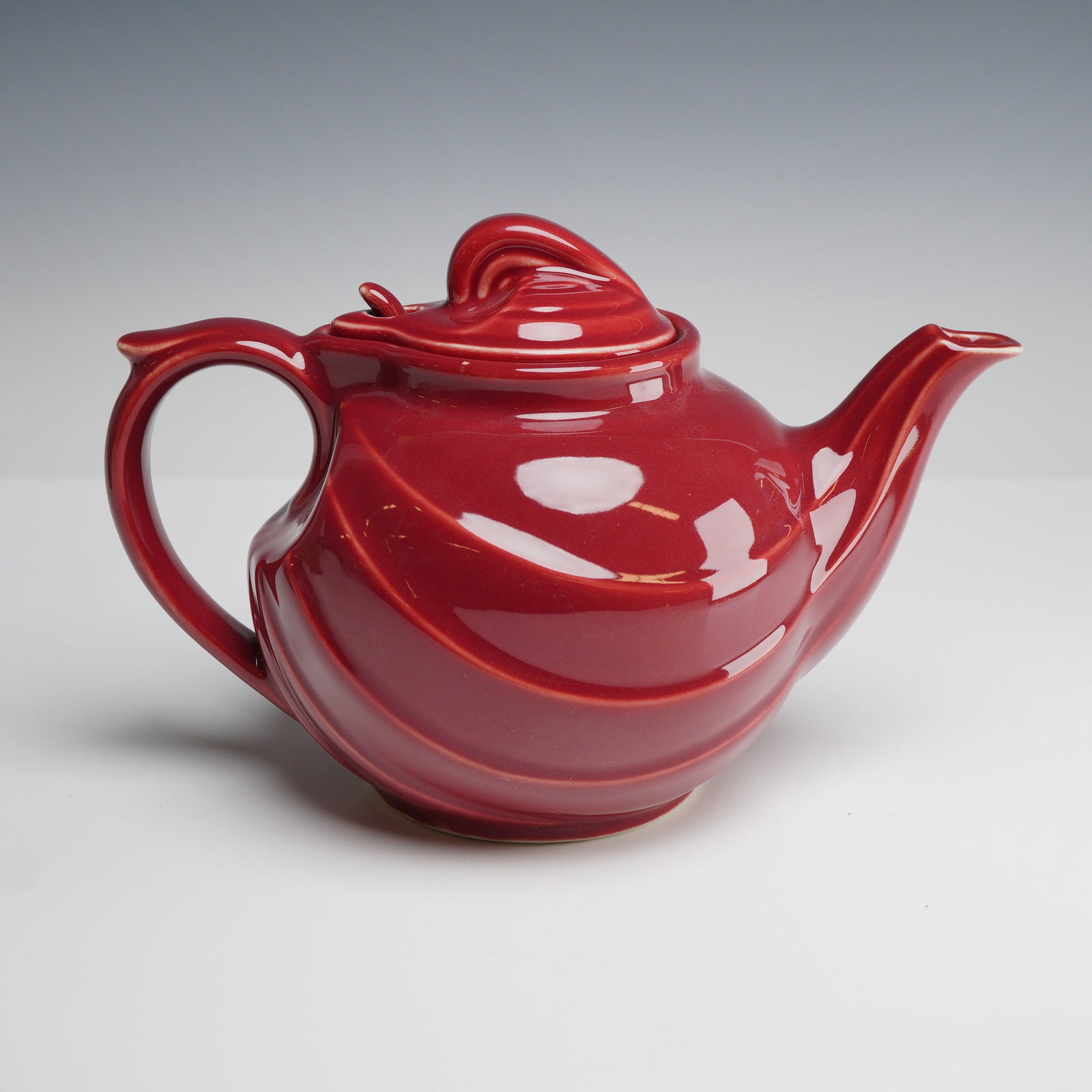 Hall China Company Swirl Burgundy Teapot and Lid: A mid-century Hall China ceramic teapot with a matching lid. The vessel features a bulbous body and spout characterized by molded, diagonal spiral ribbing. The teapot is designed with an arched handle