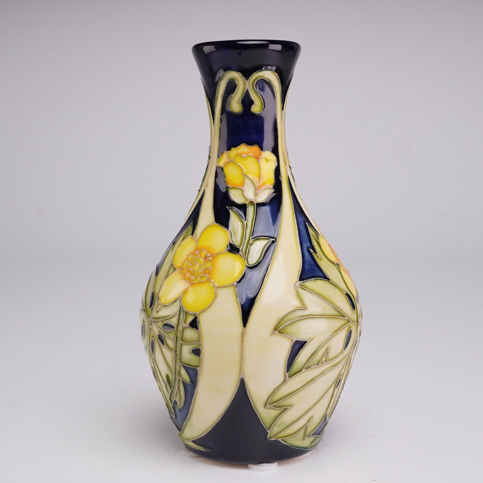 Moorcroft Pottery Florian Ware Vase, Daffodil: The vase features a baluster form with a flared rim and a tapered neck. The decoration is executed using the tube-lining technique, featuring stylized yellow flowers and broad green foliage. These ele