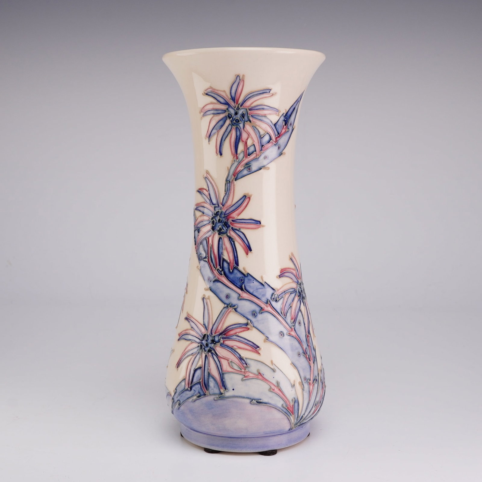 Moorcroft Pottery Collectors Club Pink and Blue Floral Vase: A Moorcroft earthenware ceramic vase produced for the Moorcroft Collectors Club. The tall, slender vessel features a flared rim, a tapering neck, and a bulbous base. The exterior is decorated using th