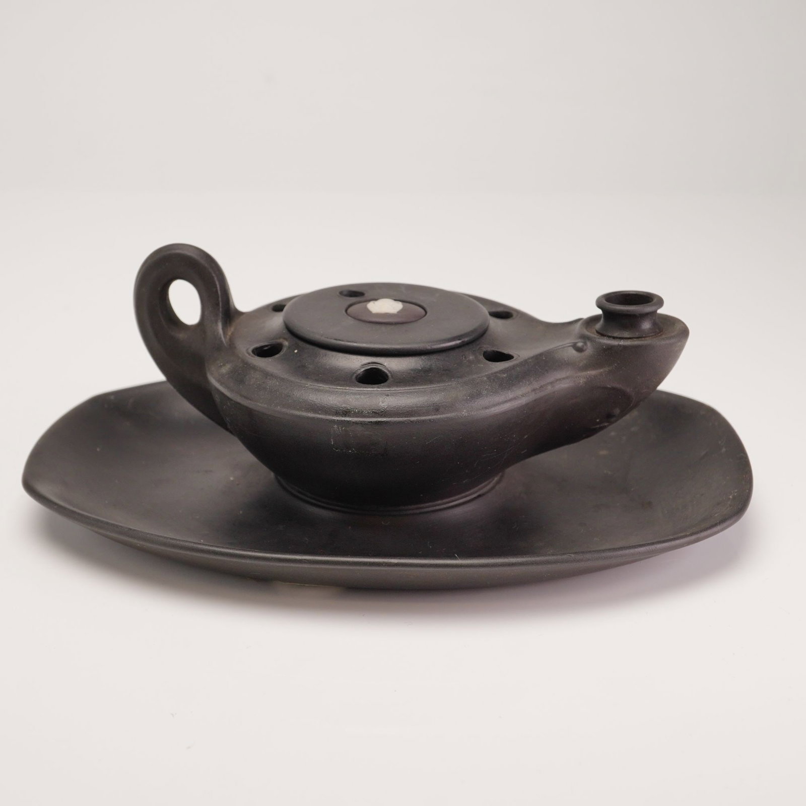 Wedgwood Black Basalt Oil Lamp and Matching Oval Stand: This set consists of a Wedgwood black basalt oil lamp and a matching oval stand. The oil lamp is modeled in a neoclassical style, featuring a central reservoir with a removable lid, a single protrudin