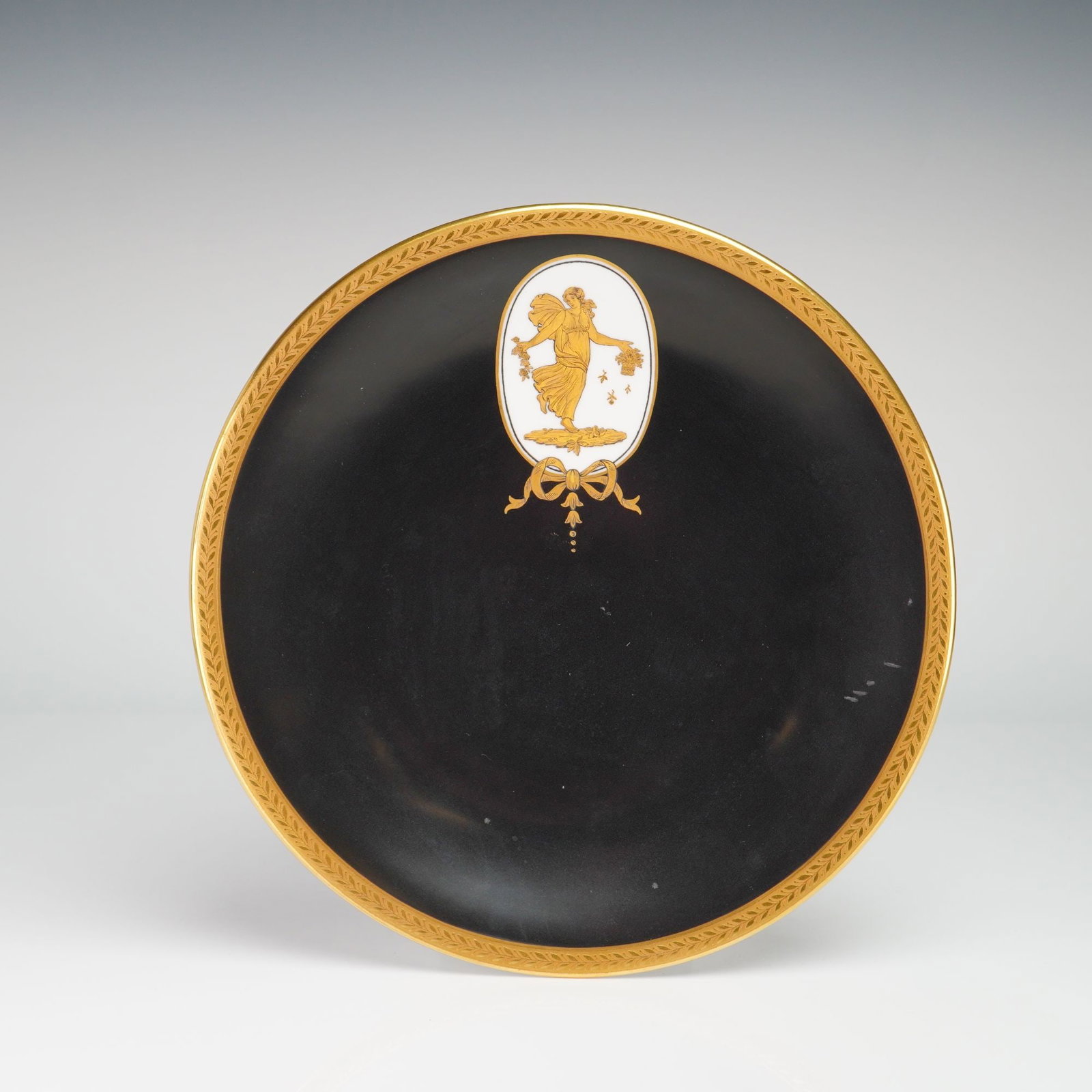 Wedgwood Black Basalt Style Porcelain Cabinet Plate from the Rubin Collection: This porcelain cabinet plate was manufactured by Wedgwood and retailed by Phillips's Ltd of London. The plate features a matte black ground in the style of black basalt, decorated with a gilt laurel l