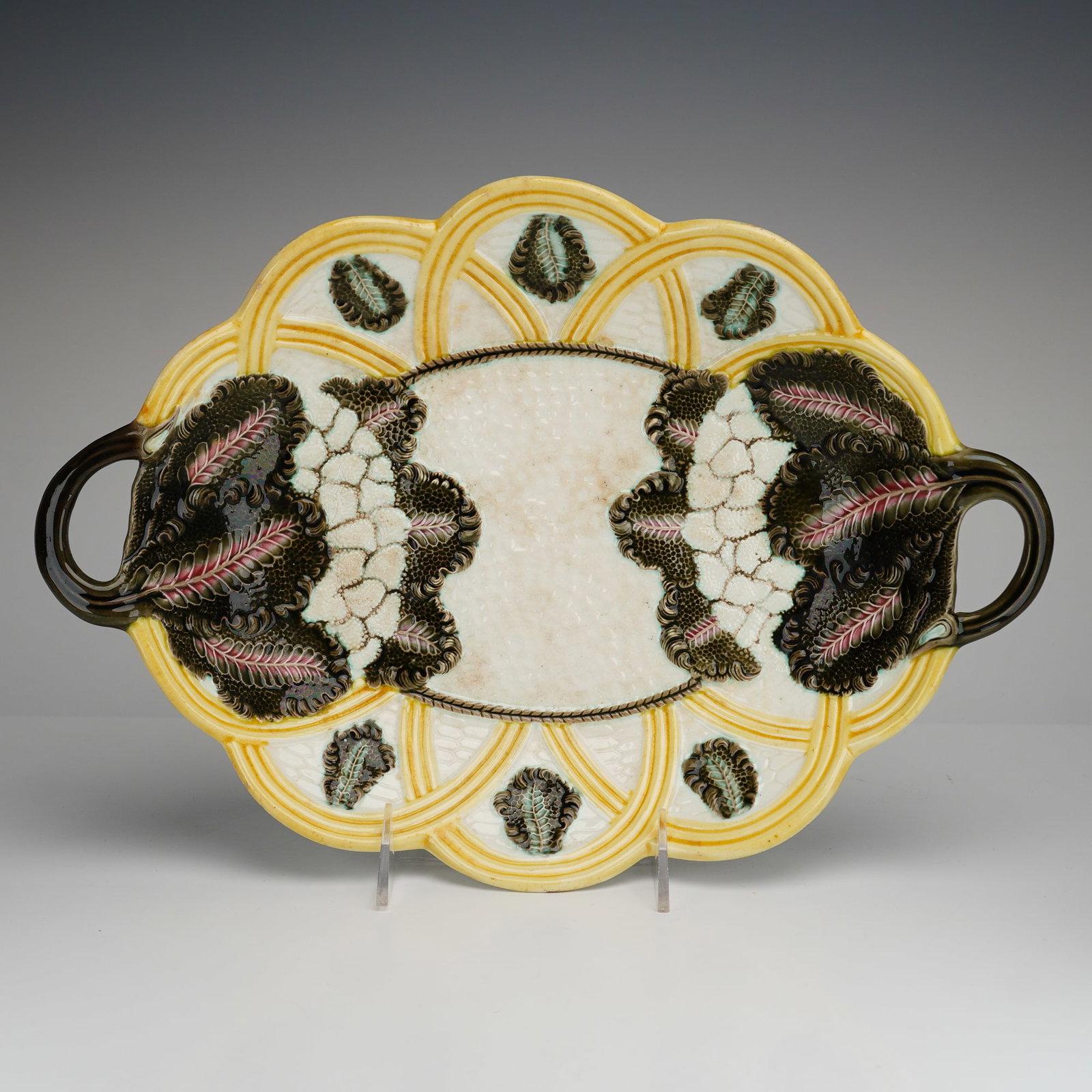 Wedgwood Majolica Handled Platter: A Victorian-era majolica earthenware serving platter manufactured by Wedgwood. The oval form is decorated in the Argenta style with relief-molded cauliflower florets at the center, flanked by large da