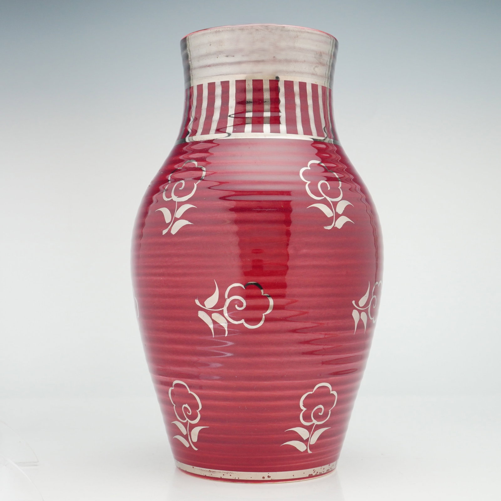 Wedgwood Red Veronese Vase: The vessel is constructed with an ovoid body detailed with horizontal concentric ridges, a tapering neck, and a slightly flared rim. The silver overlay includes a band of alternating vertical stripes 