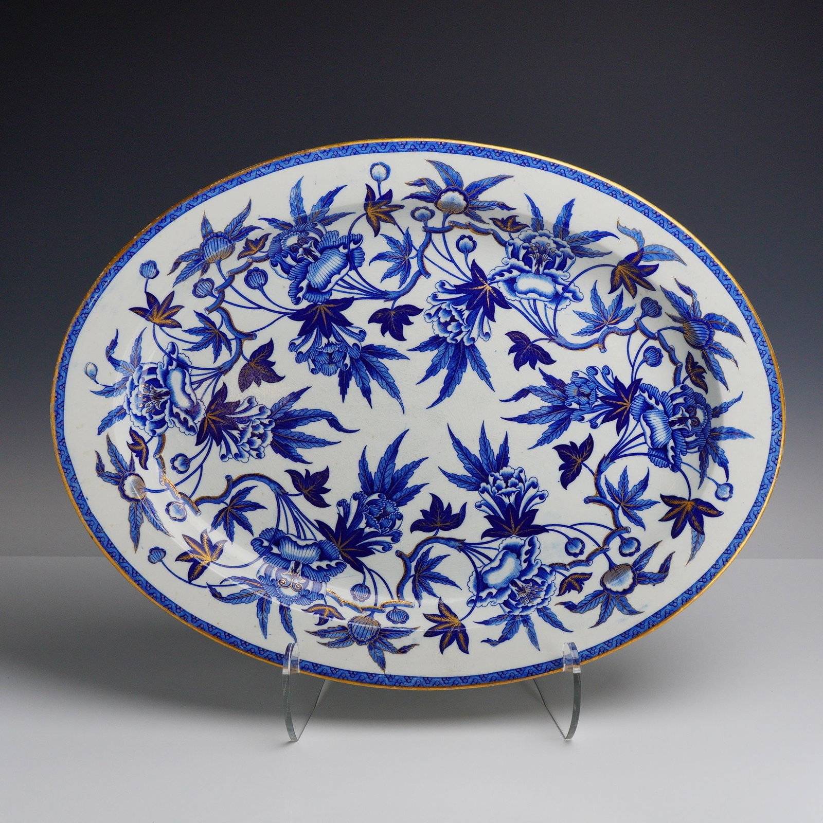 Wedgwood Peony Pattern Blue and Gold Transfer-Printed Oval Platter: This large oval serving platter from the Rubin collection is manufactured by Wedgwood in the Peony pattern. The piece is crafted from glazed earthenware and features a cobalt blue transfer-printed flo