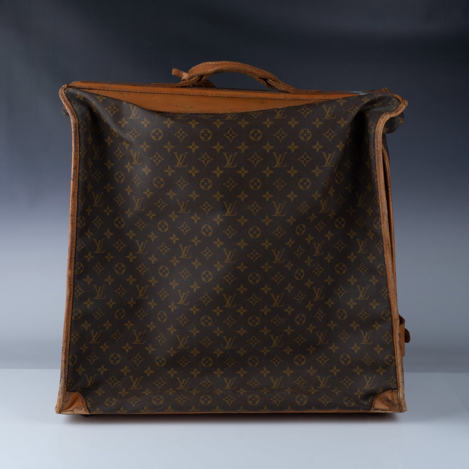 Louis Vuitton Monogram Canvas Garment Bag: A vintage Louis Vuitton monogram canvas garment bag with natural Vachetta leather trim and brass hardware. This classic piece features a fold-out design with leather straps and zippered compartments f