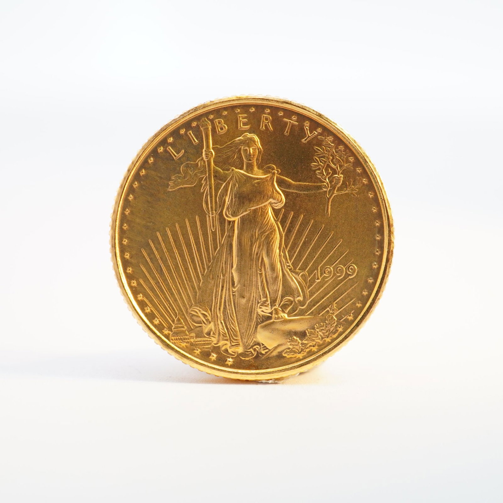 1999 1/10 Fine Gold $5 American Gold Eagle Coin: Minted by the Philadelphia Mint. The obverse side depicts an effigy of Liberty with the date to the right. The reverse side depicts an eagle in flight above a nest of birds with the country name at th