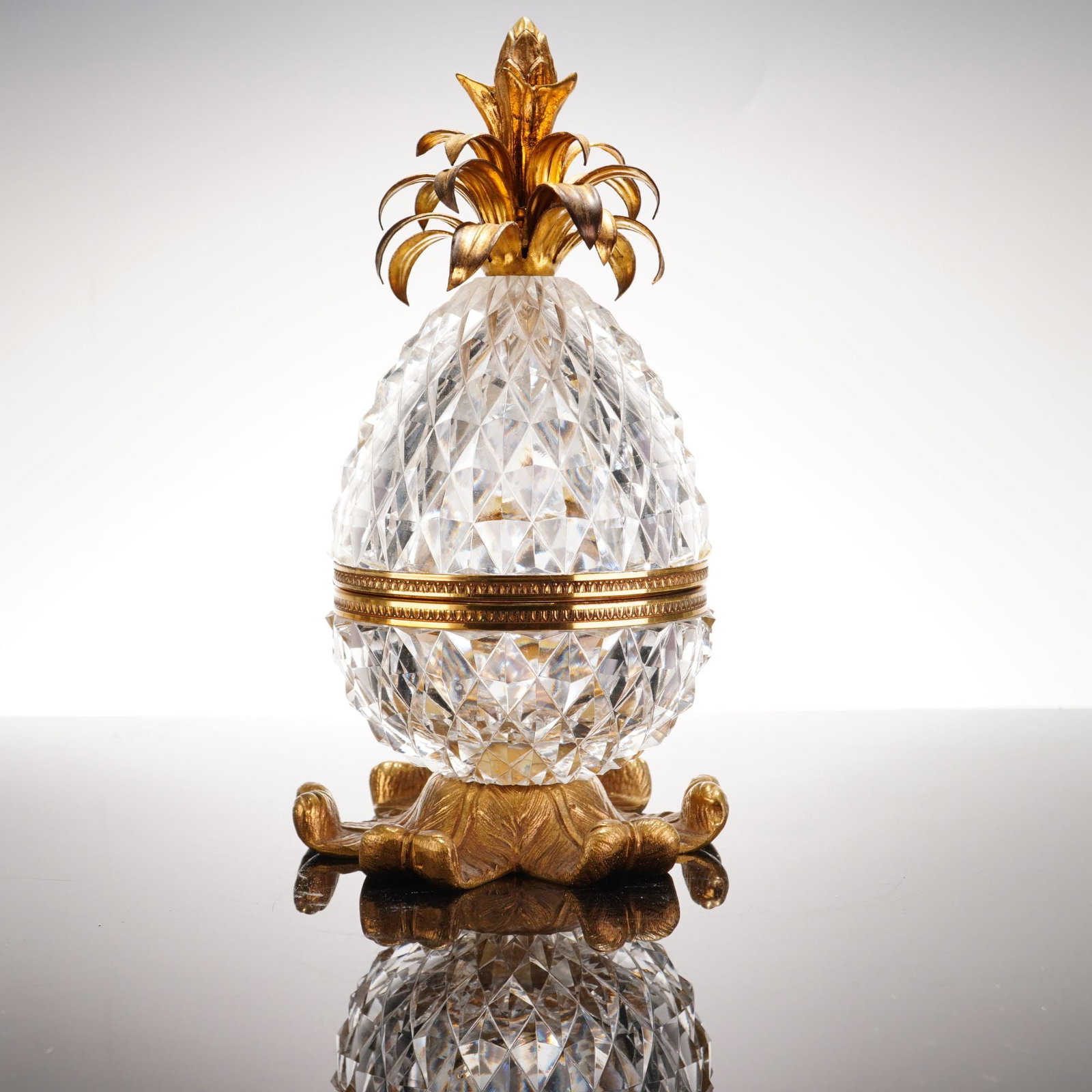 French Gilt Metal and Diamond Cut Crystal Pineapple Shaped Casket: A French decorative crystal and metal pineapple shaped casket, often used as a trinket box. The body is composed of two sections of heavy clear crystal featuring a deep, all-over diamond-point cutting
