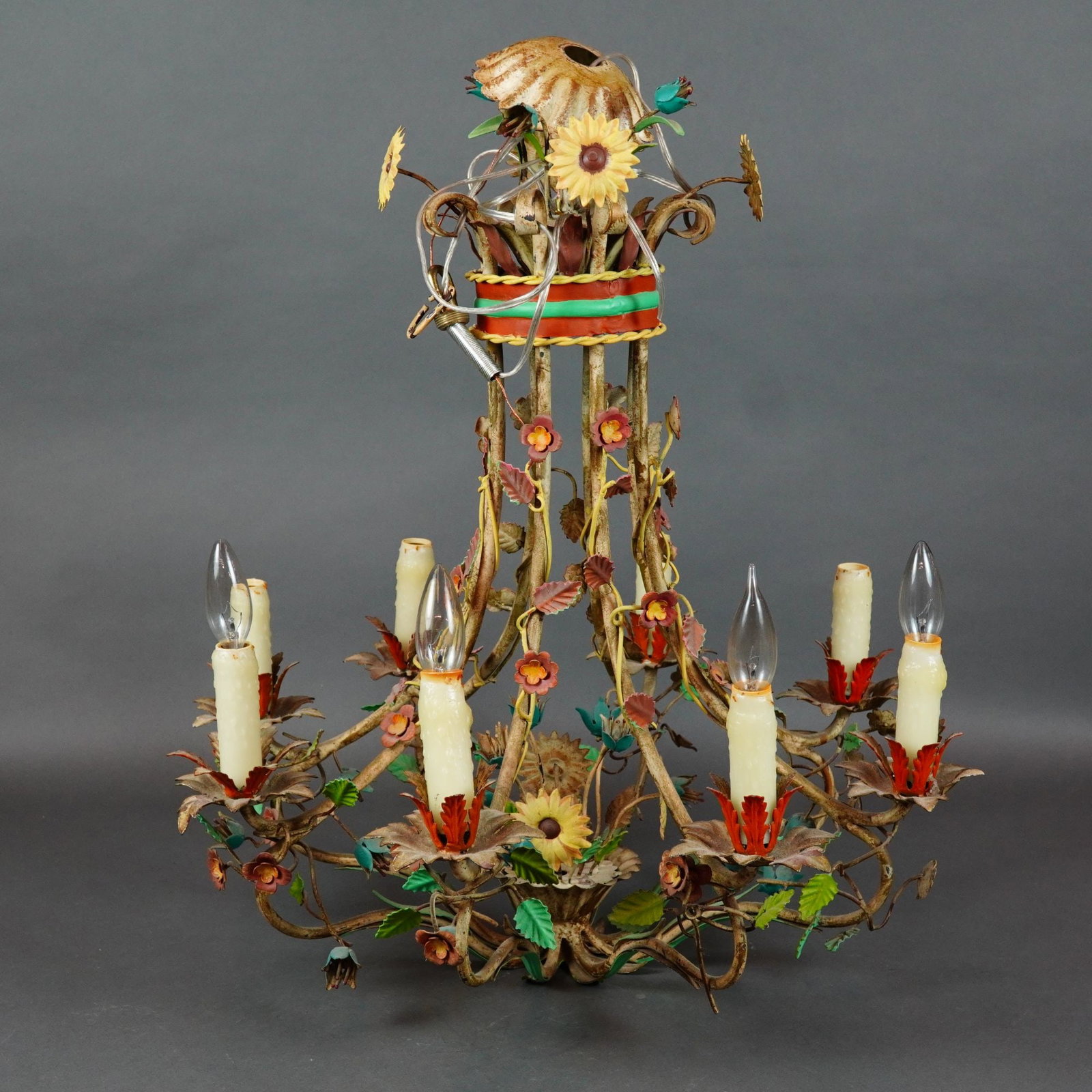 Italian Style 8-Light Polychrome Metal Floral Tole Chandelier: A vintage 8-light hanging metal chandelier with flowers and leaves, designed in the mid-century Italian tole style. The central structure consists of a bundle of metal stems bound by a polychrome band