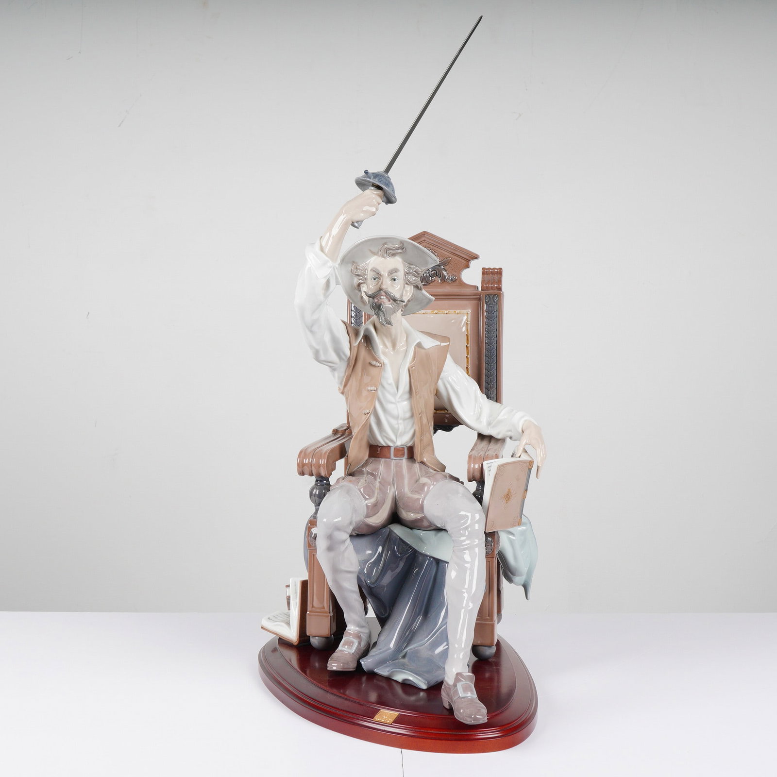 Lladro Porcelain Figurine, I Am Don Quixote! 1001522: A Lladro porcelain figurine titled I Am Don Quixote 1001522 in muted tones of white, tan, and grey, mounted on a wooden base with weight and dimensions including the base. Dimensions: 18.50"L x 12.00"