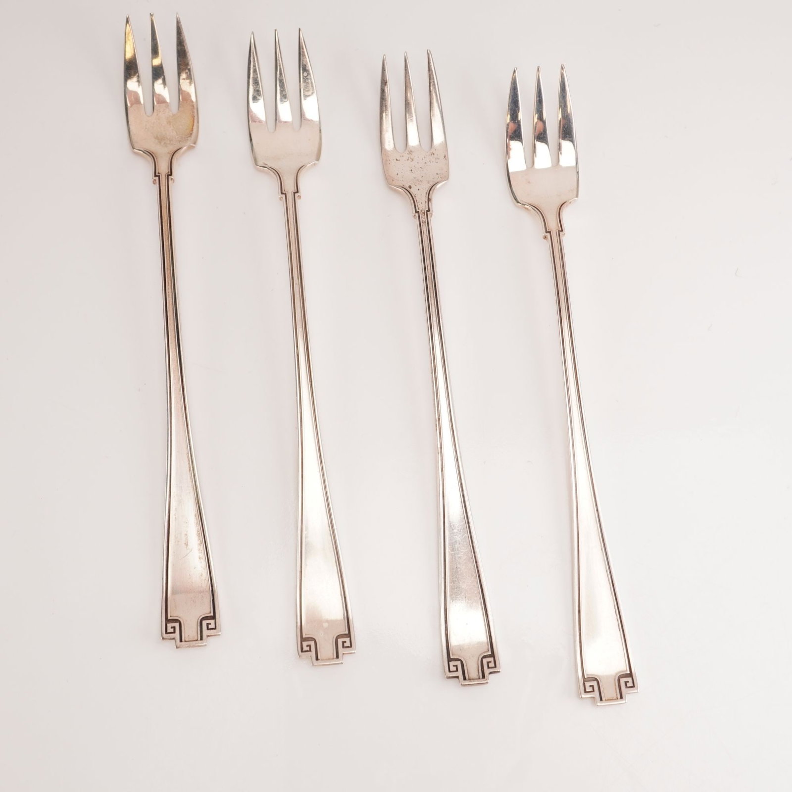 4pc Gorham Sterling Silver Cocktail Forks, Etruscan: Included is a 4-piece set of Gorham sterling silver cocktail forks in the Etruscan pattern, manufactured between 1913 and 1991. The design draws from Greco-Roman revival influences, showcasing a refin