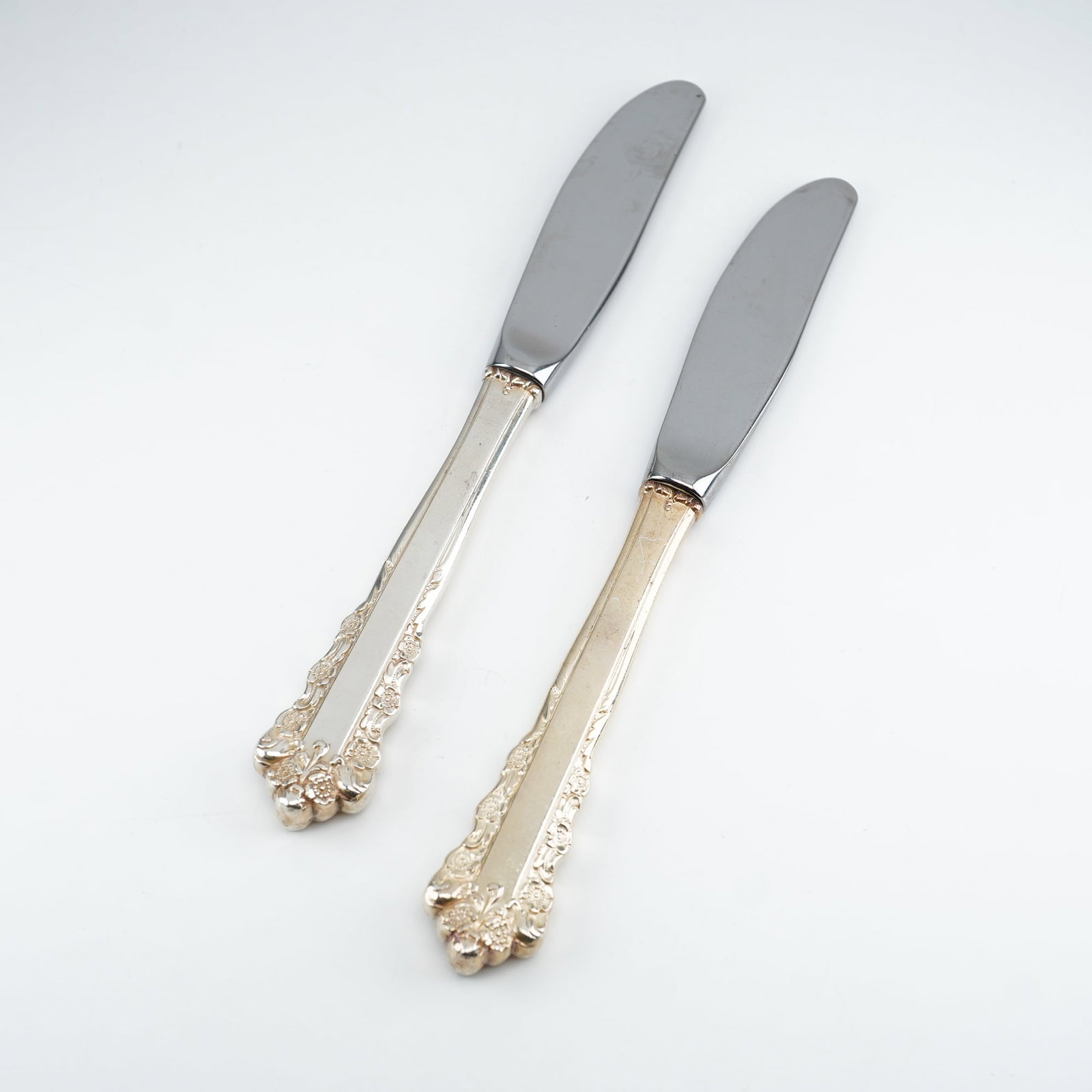 2pc Lunt Sterling Silver and Stainless Steel Butter Spreaders, Belle Meade: Produced by Lunt Silversmiths between 1967 and 1997, each piece features ornate Rococo-style decoration with raised floral clusters and flowing scrollwork along the handle edges and terminals. Additio
