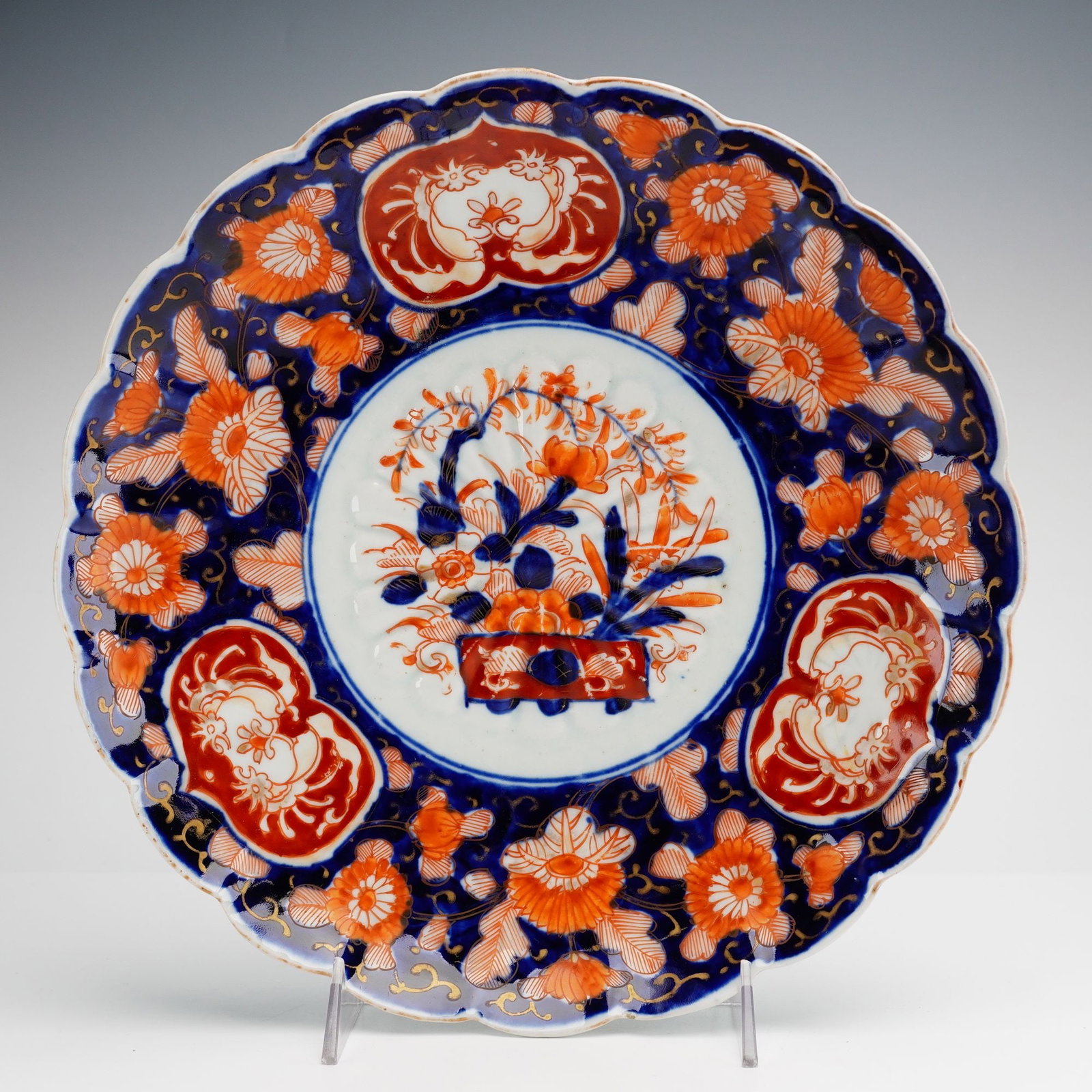 Japanese Imari Style Porcelain Bowl with Scalloped Rim: A Japanese porcelain bowl decorated in the traditional Imari style using underglaze cobalt blue, overglaze iron-red enamel, and gilded highlights. The piece features a circular form with a lobed and s