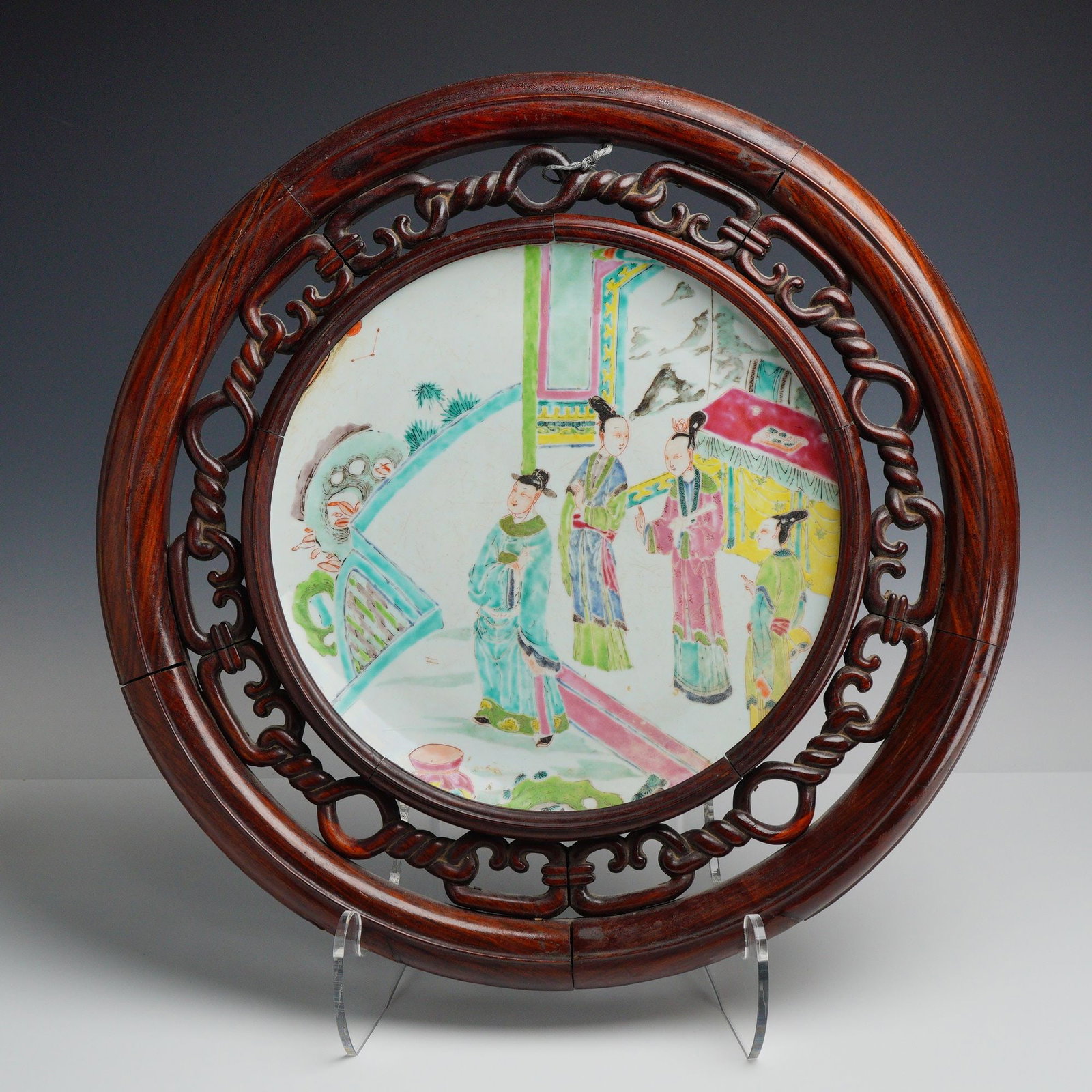 Chinese Famille Rose Porcelain Plaque in a Carved Wood Frame: A circular Chinese porcelain plaque decorated with overglaze famille rose enamels, likely dating from the late 19th to early 20th century (Late Qing Dynasty to Republic Period). The central narrative 