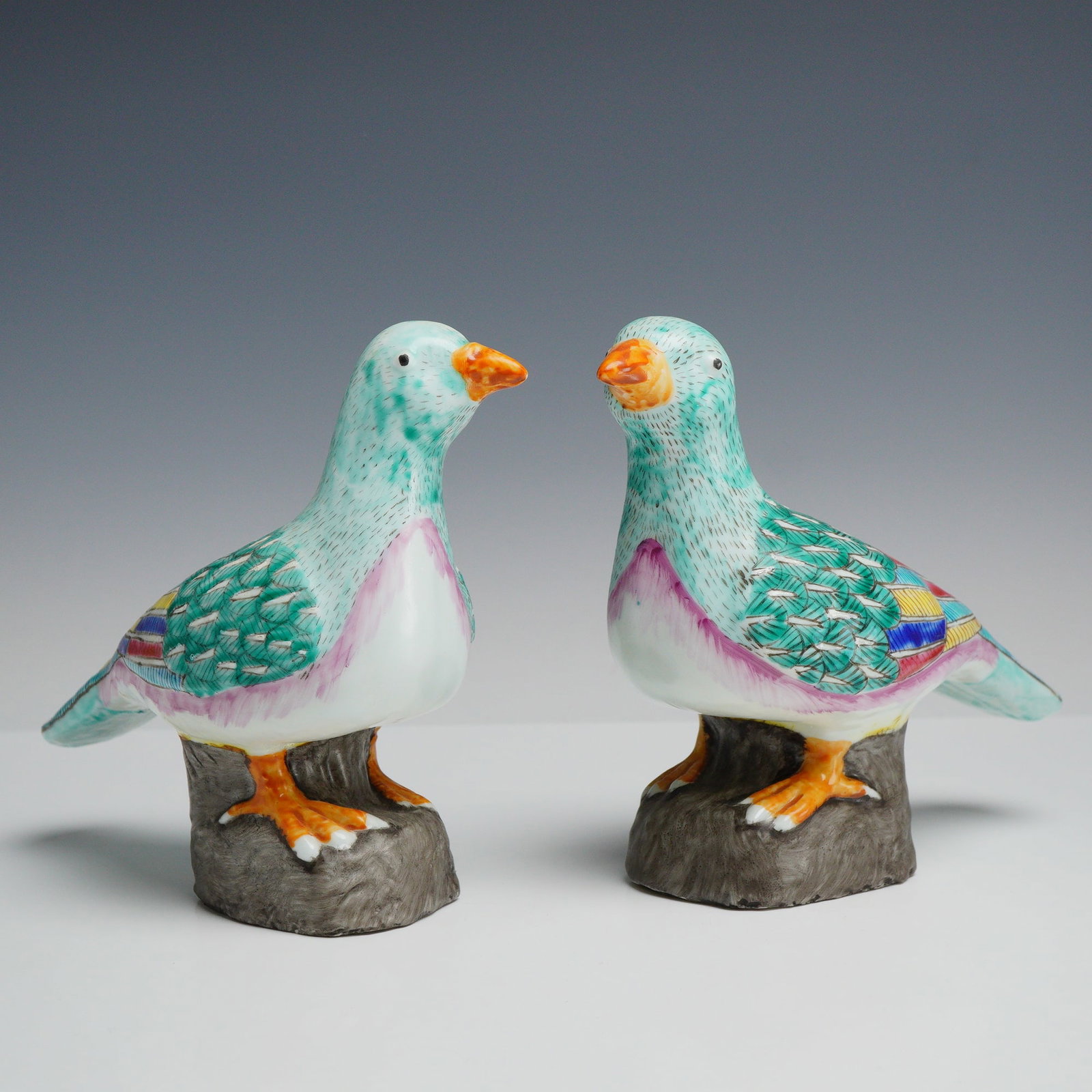 2pc Chinese Qing Dynasty Style Ceramic Dove Figurines: This pair of porcelain bird figurines, representing doves, is modeled in the style of Chinese Famille Rose export wares. Each bird is perched atop a textured base fashioned to resemble rockwork. The d