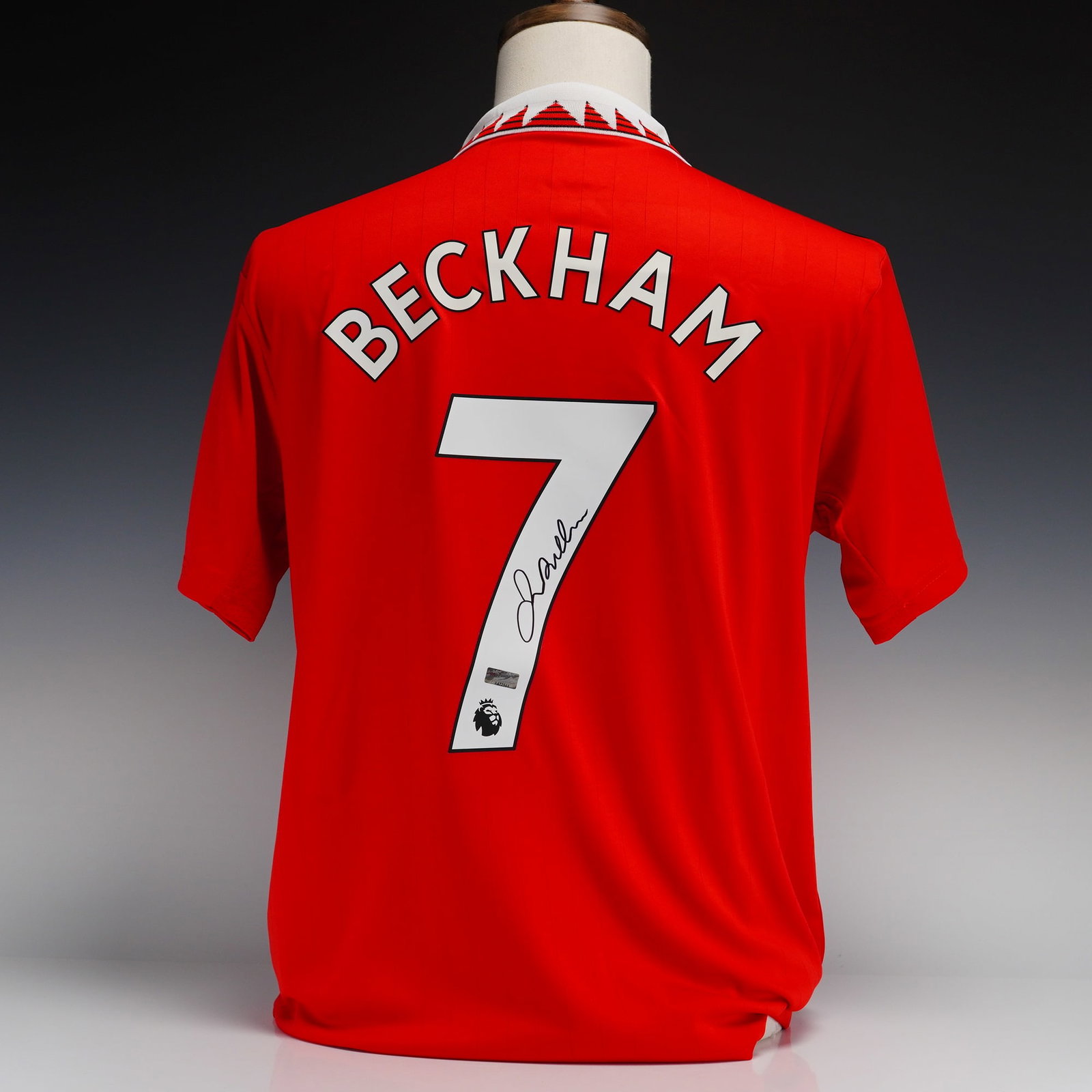 David Beckham Autographed Manchester United 2022-23 Home Jersey with Panini Authentic COA: This is a size Large Manchester United home jersey from the 2022-23 season manufactured by Adidas. The red jersey features a white polo collar with a red and black triangular pattern, black stripes