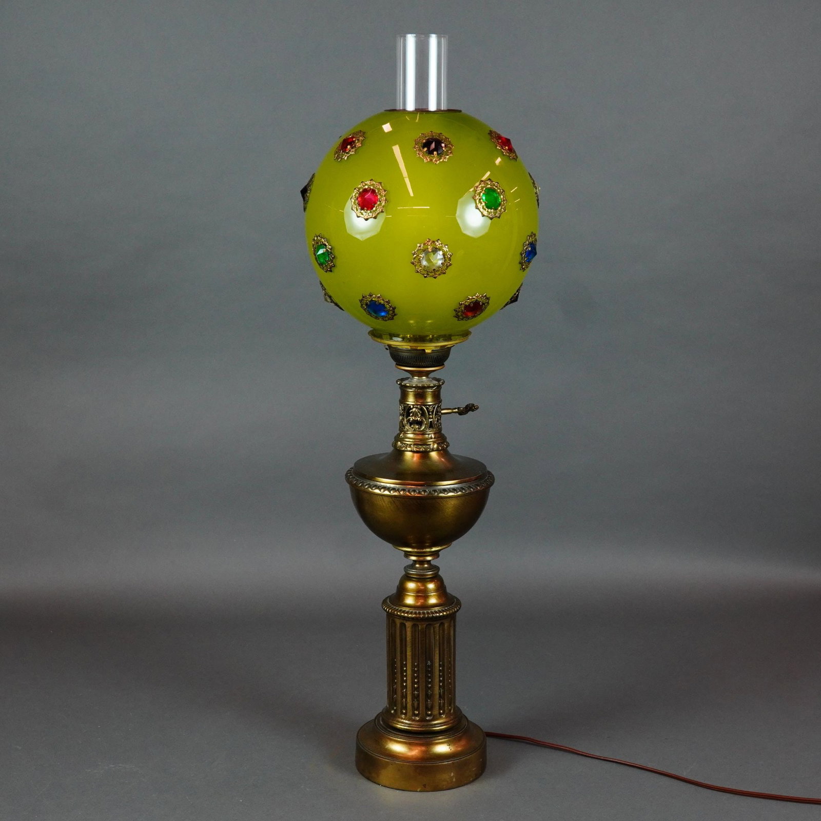 Antique Victorian Electrified Banquet Lamp with Jeweled Glass Shade and Metal Base: This antique Victorian-style electrified banquet lamp features a spherical jeweled glass shade. The shade is composed of mold-blown lime green glass with a satin finish, adorned with multiple