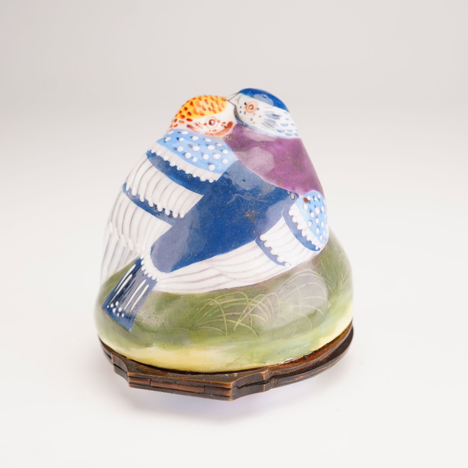 Antique English Enamel Bonbonniere, Lovebirds: This piece is modeled as two birds nestled together on a domed, grassy mound. The exterior is decorated in hand-painted polychrome enamels featuring vibrant shades of cobalt blue, manganese purple,