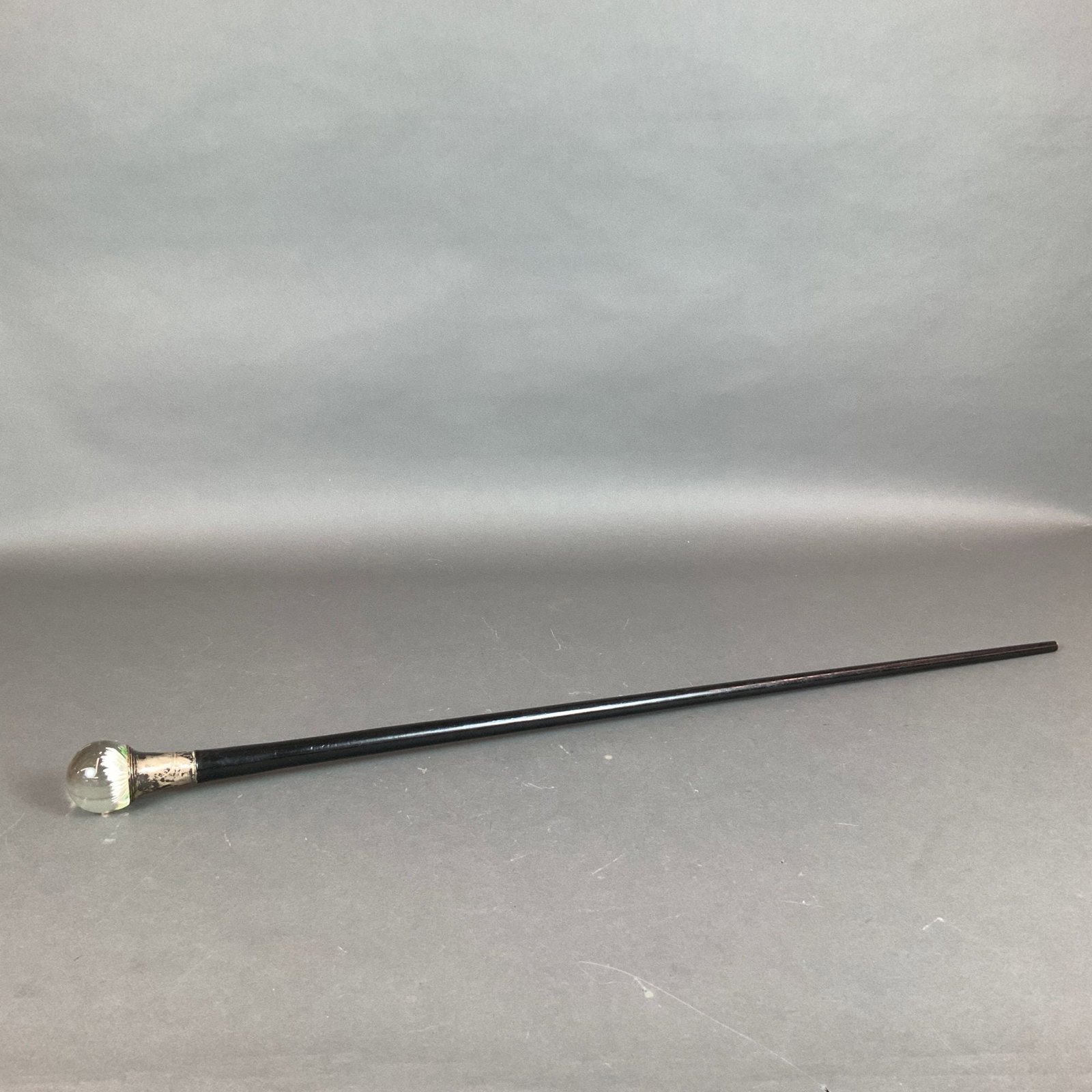 Wooden Walking Cane with Floral Paperweight Handle: An antique wooden cane featuring a decorative millefiori-style glass paperweight handle with flower. The clear glass spherical handle contains a multi-petaled white flower with a green center. The han