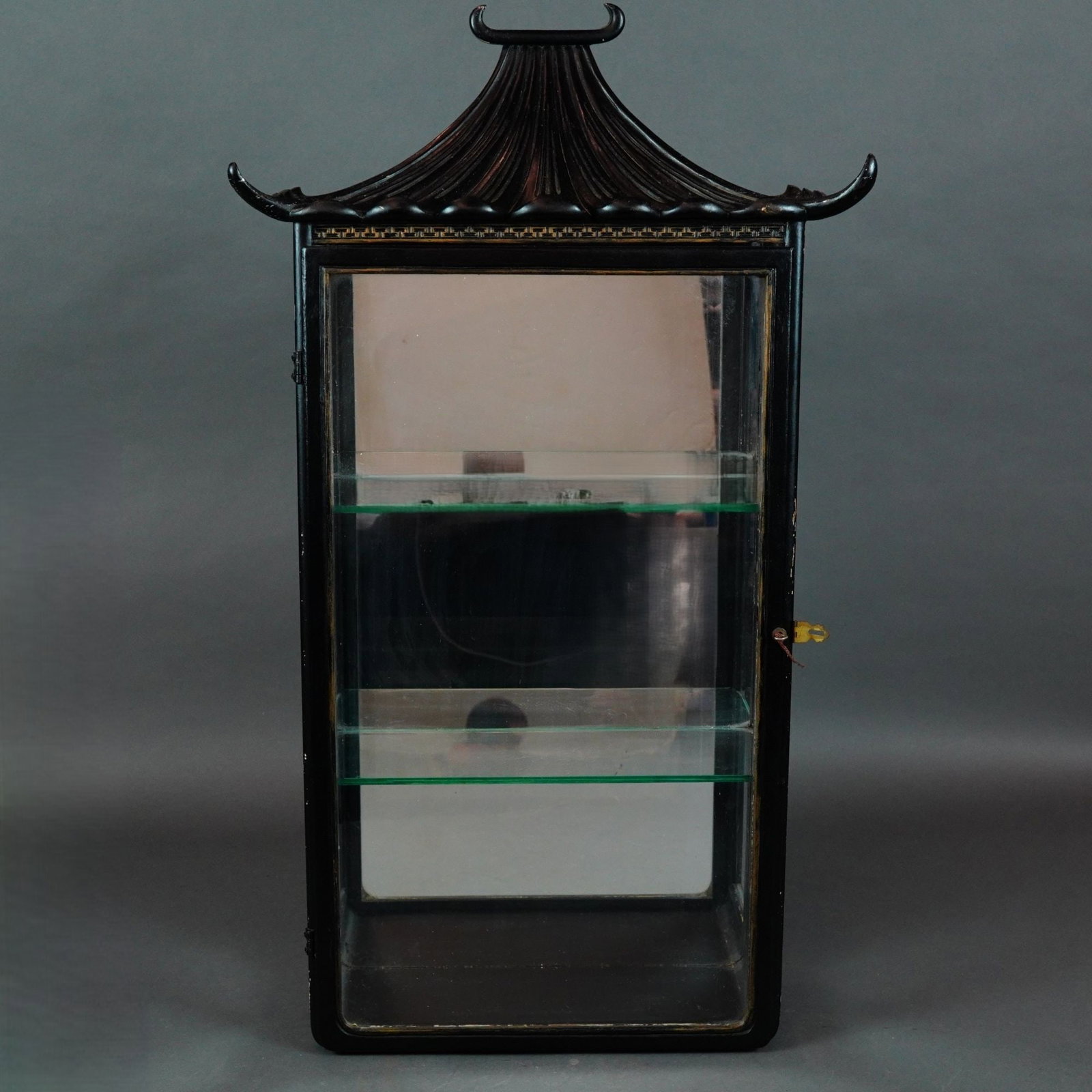 Chinoiserie Black Lacquered Pagoda-Top Wall Vitrine with Mirror Back: A mid-20th century wall-hanging display cabinet or vitrine designed in the Chinoiserie taste. The piece is constructed of black lacquered wood featuring a prominent pagoda-form roof with a fluted