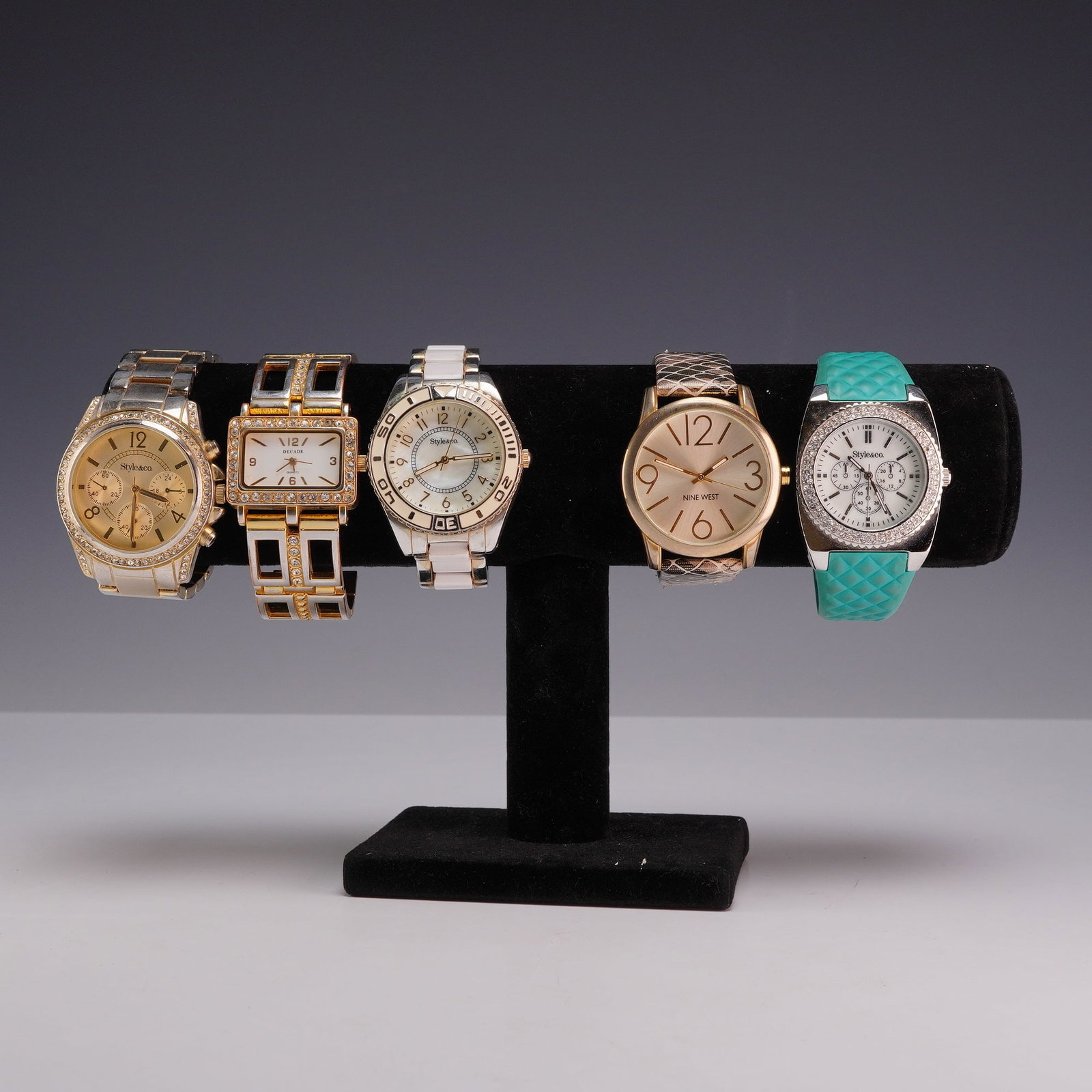 5pc Mixed Fashion Wrist Watches Including Style & Co. and Nine West: A 5pc collection of women's fashion wristwatches from brands including Style & Co., Nine West, and Decade. The group includes a Style & Co. gold-tone chronograph style watch with a crystal-encrusted b