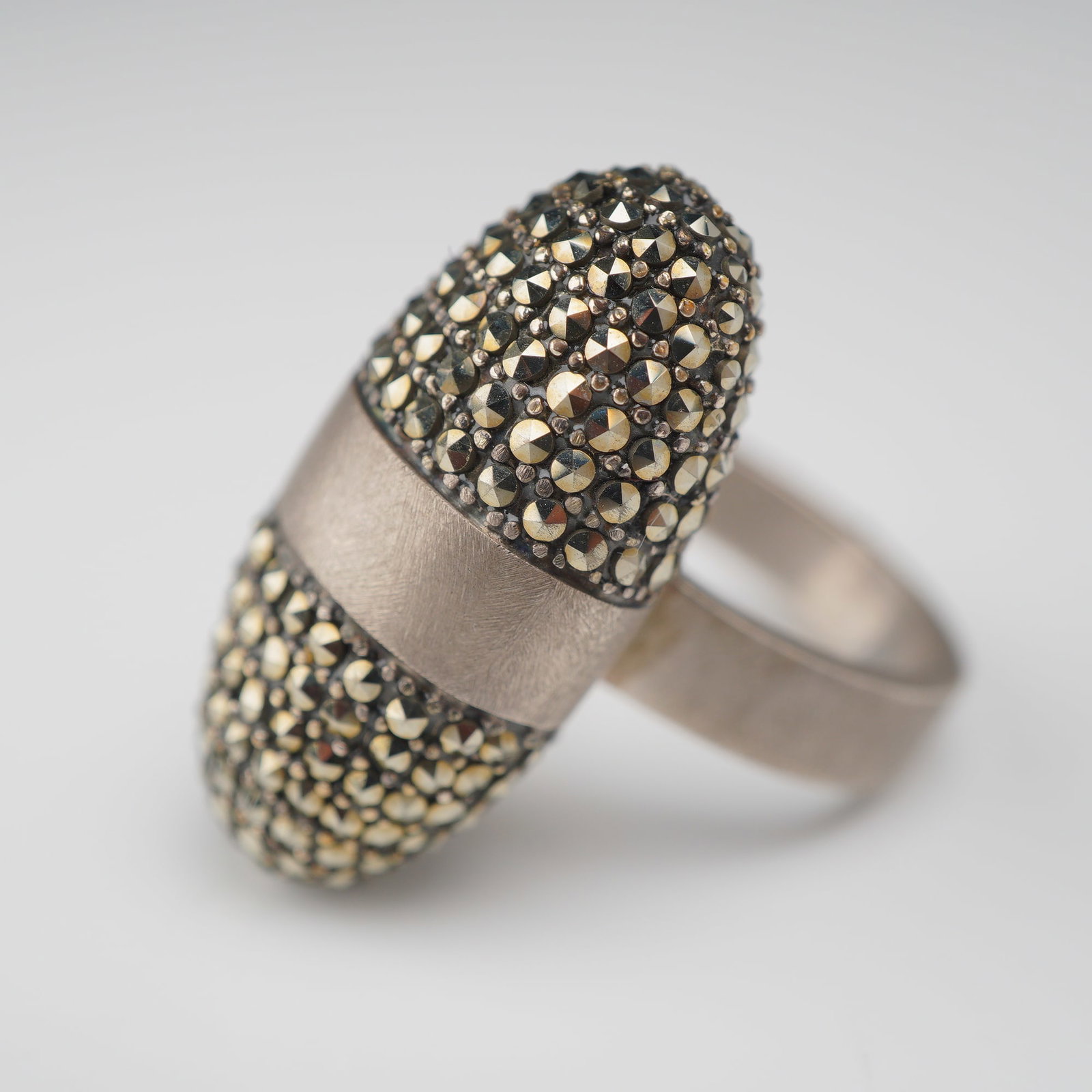 Nanis Sterling Silver and Marcasite Domed Cocktail Ring: This bold cocktail ring is produced by the Italian jewelry house Nanis. Crafted in sterling silver, the design features an elongated, domed head bisected by a wide central band with a brushed satin fi