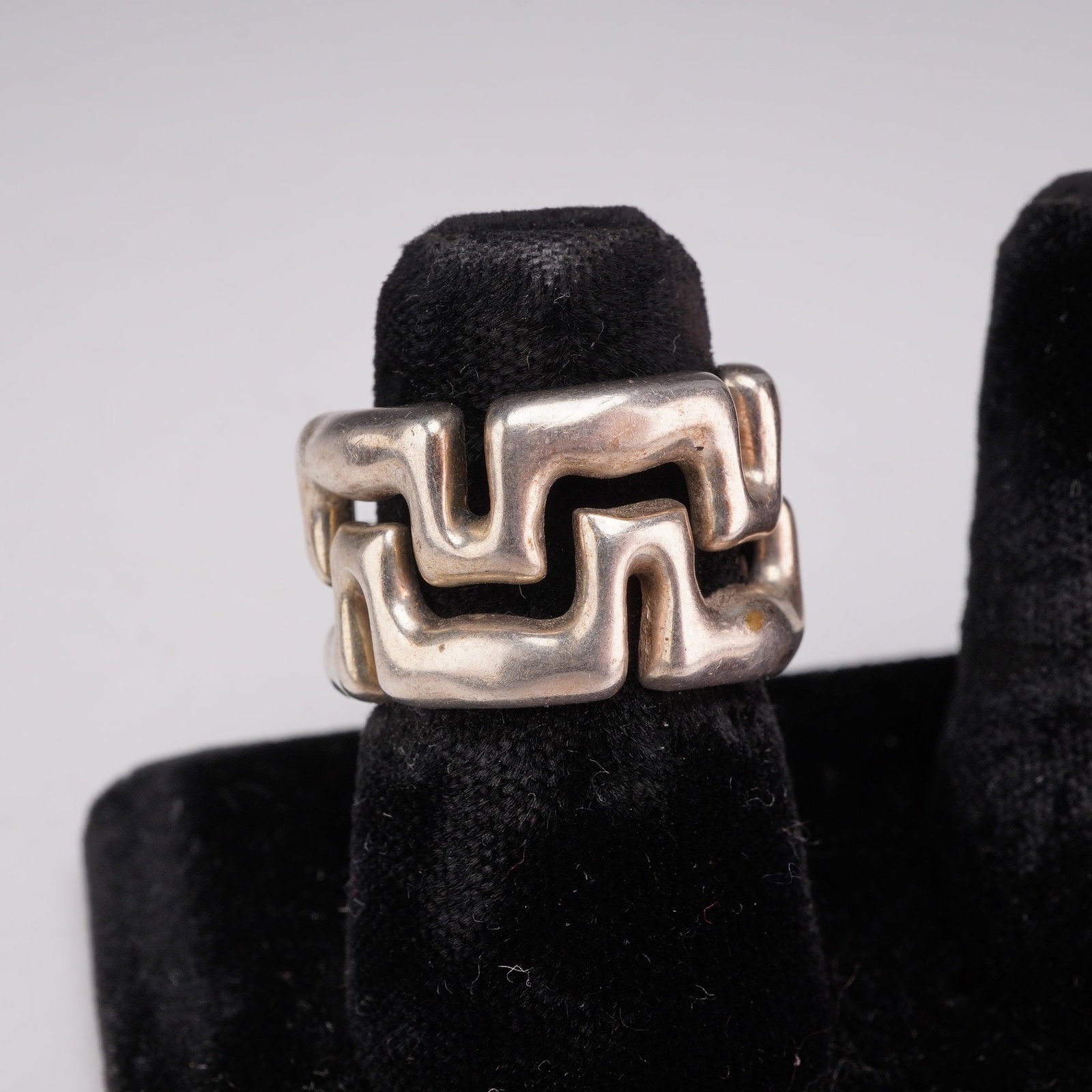 Tiffany and Co. Sterling Silver Geometric Puzzle Single Hoop Earring: This single Tiffany and Co. sterling silver hoop earring features the designer's distinctive interlocking geometric puzzle motif. The piece is constructed with a thick, cast openwork profile and is eq