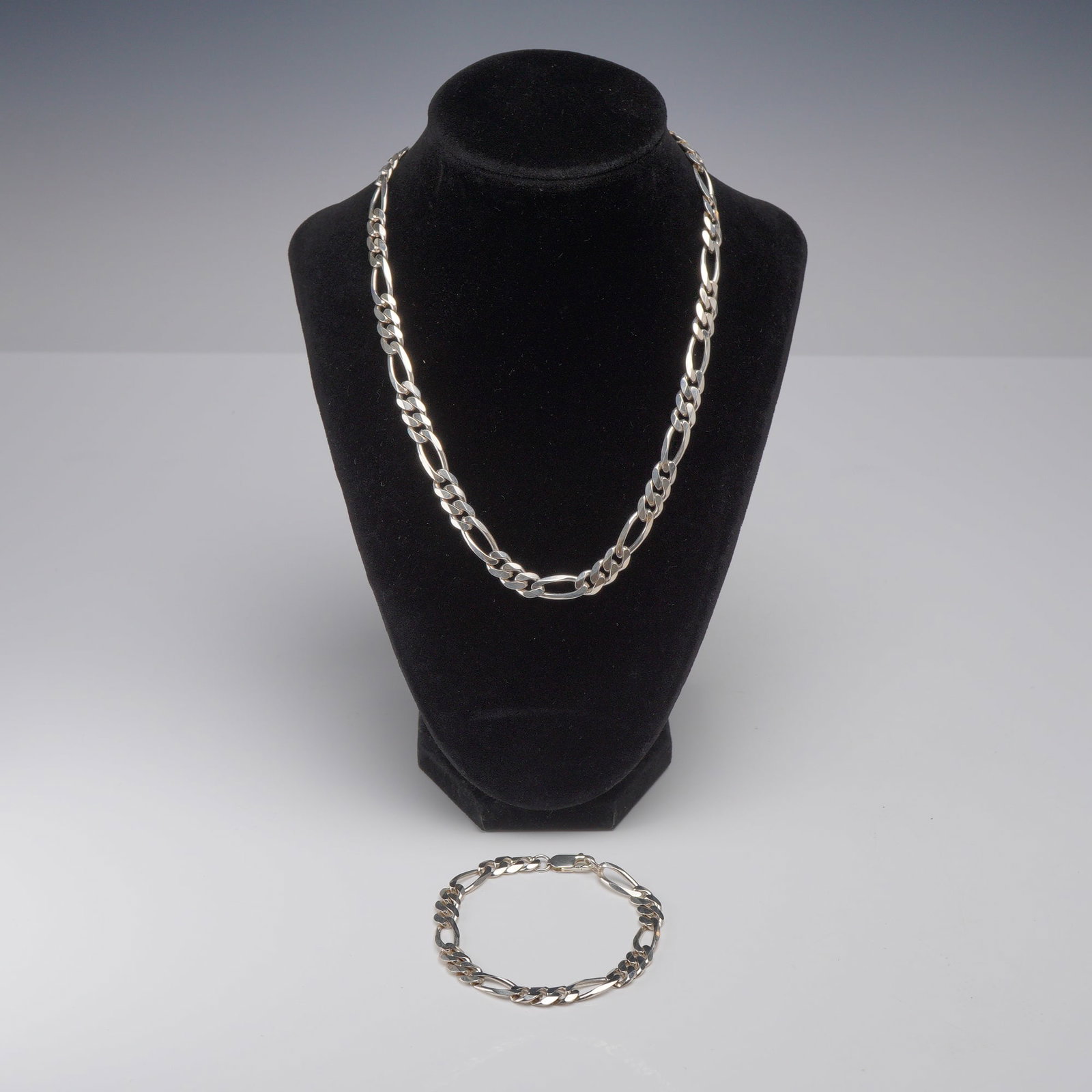 2pc Sterling Silver Figaro Link Necklace and Bracelet Set: This jewelry set consists of a matching necklace and bracelet crafted from sterling silver. Both pieces feature a classic Figaro link design, which is characterized by a repeating pattern of three sho