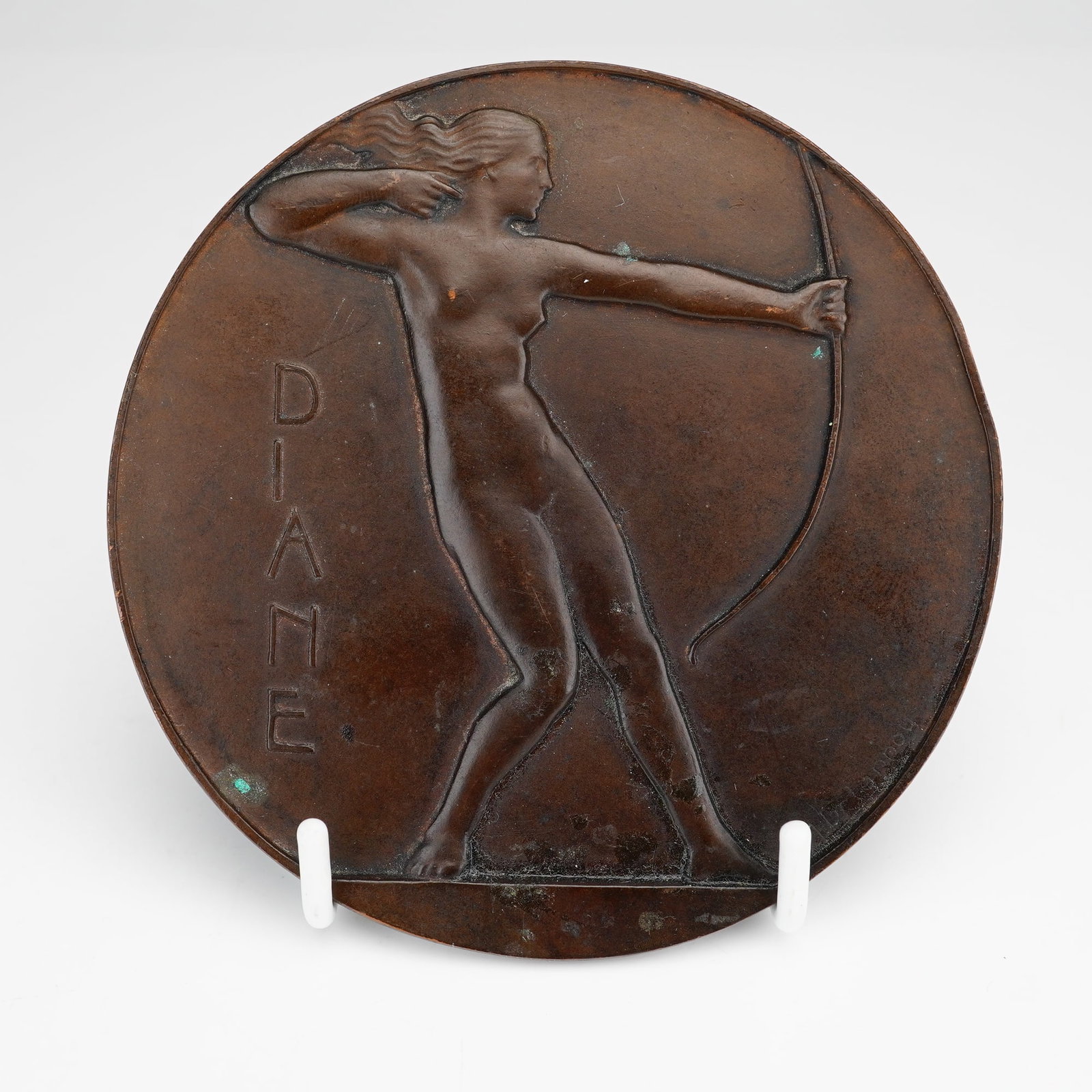 Maurice Delannoy (French, 1885-1972) Cast Bronze Art Deco Medal, Diane: This cast bronze art medal, titled Diane, was created by French artist Maurice Delannoy (1885-1972). The circular plaque features a stylized Art Deco depiction of the goddess Diane as a nude female ar