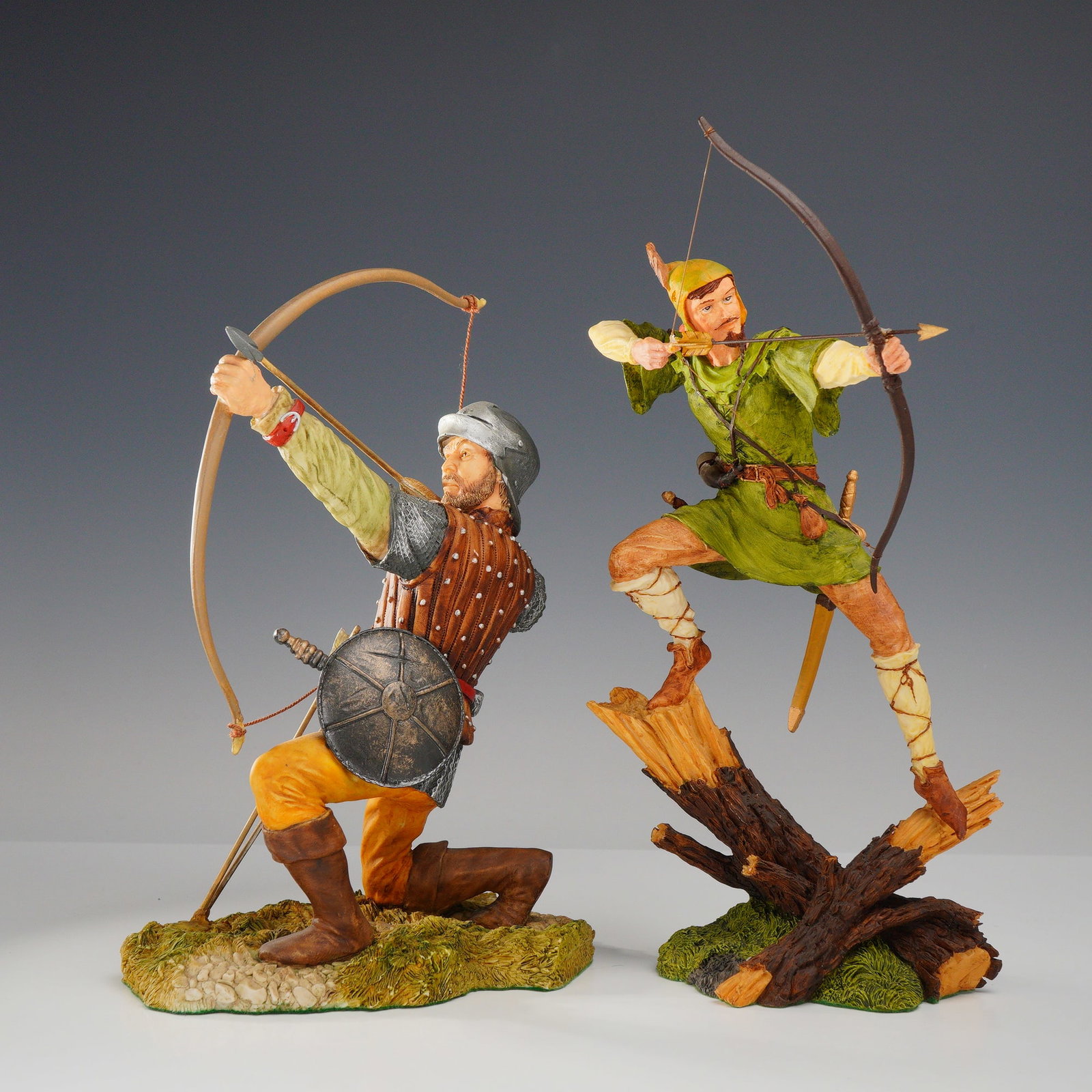 2pc Royal Doulton Hand-Made Sculpture Series, Robin Hood and Medieval Archer by Ken Fallon: This pair of hand-painted resin sculptures from the Royal Doulton Hand-made Sculpture collection features historical figures in dynamic archery poses designed by artist Kevin Fallon. The first figurin