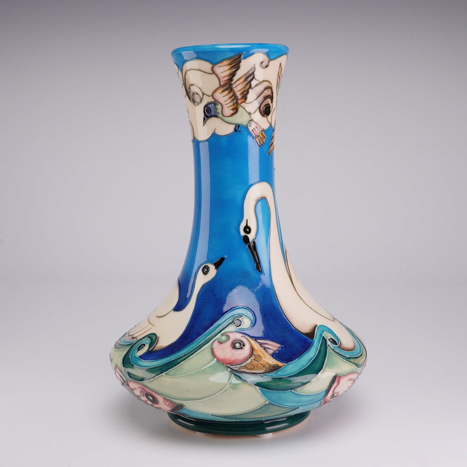 Moorcroft Pottery by Beverley Wilkes Limited Edition Vase, Odyssey Swan: The vessel is constructed with a bulbous base that tapers into a slender, slightly flared neck. The exterior is decorated using the tubelining technique, depicting two white swans floating on stylized