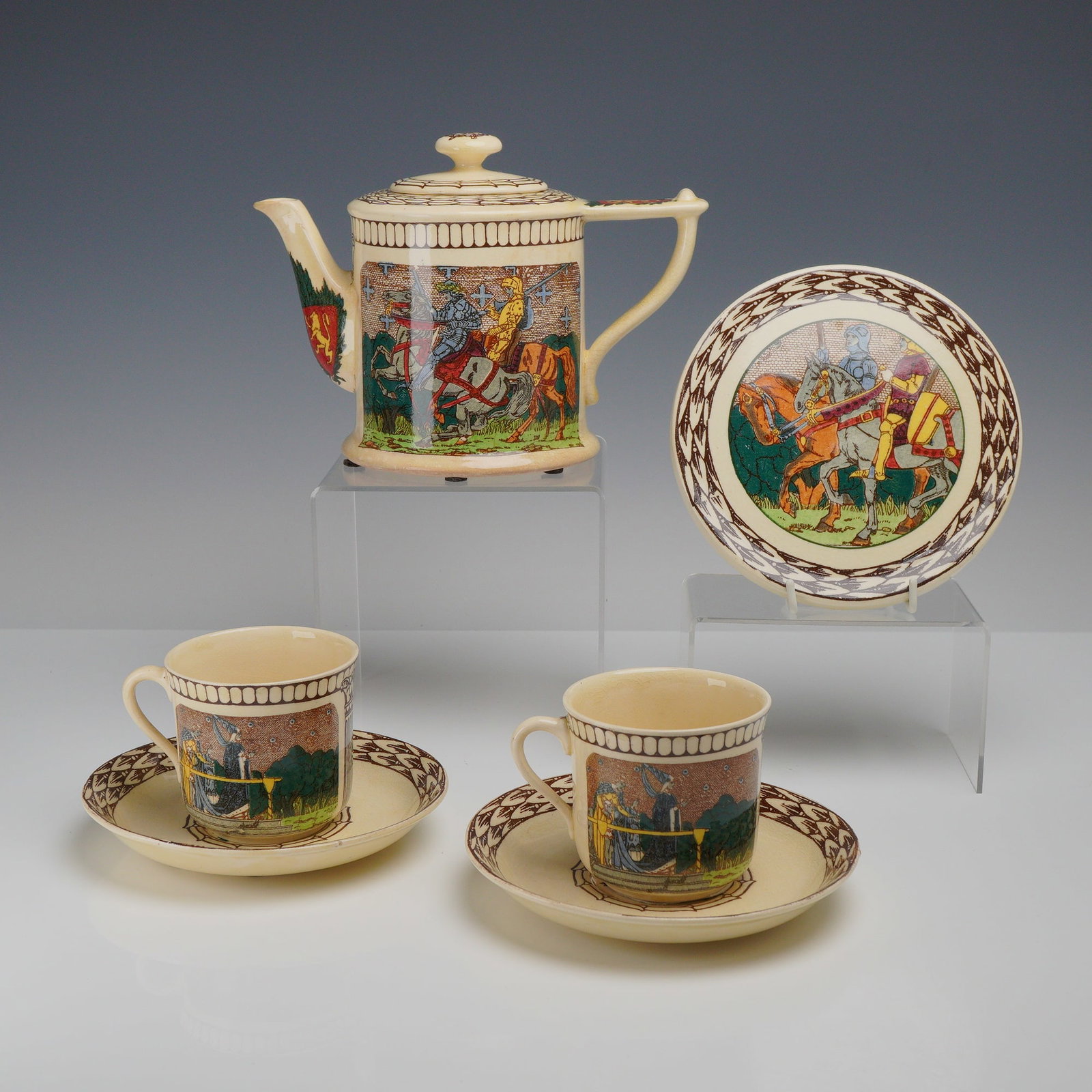 6pc Royal Doulton King Arthur's Kinghts Seriesware Teapot, Cups, and Saucers Set: This six-piece Royal Doulton earthenware set features the King Arthur's Knights pattern. The collection includes one cylindrical teapot with a stepped lid, two teacups with loop handles, two circular 