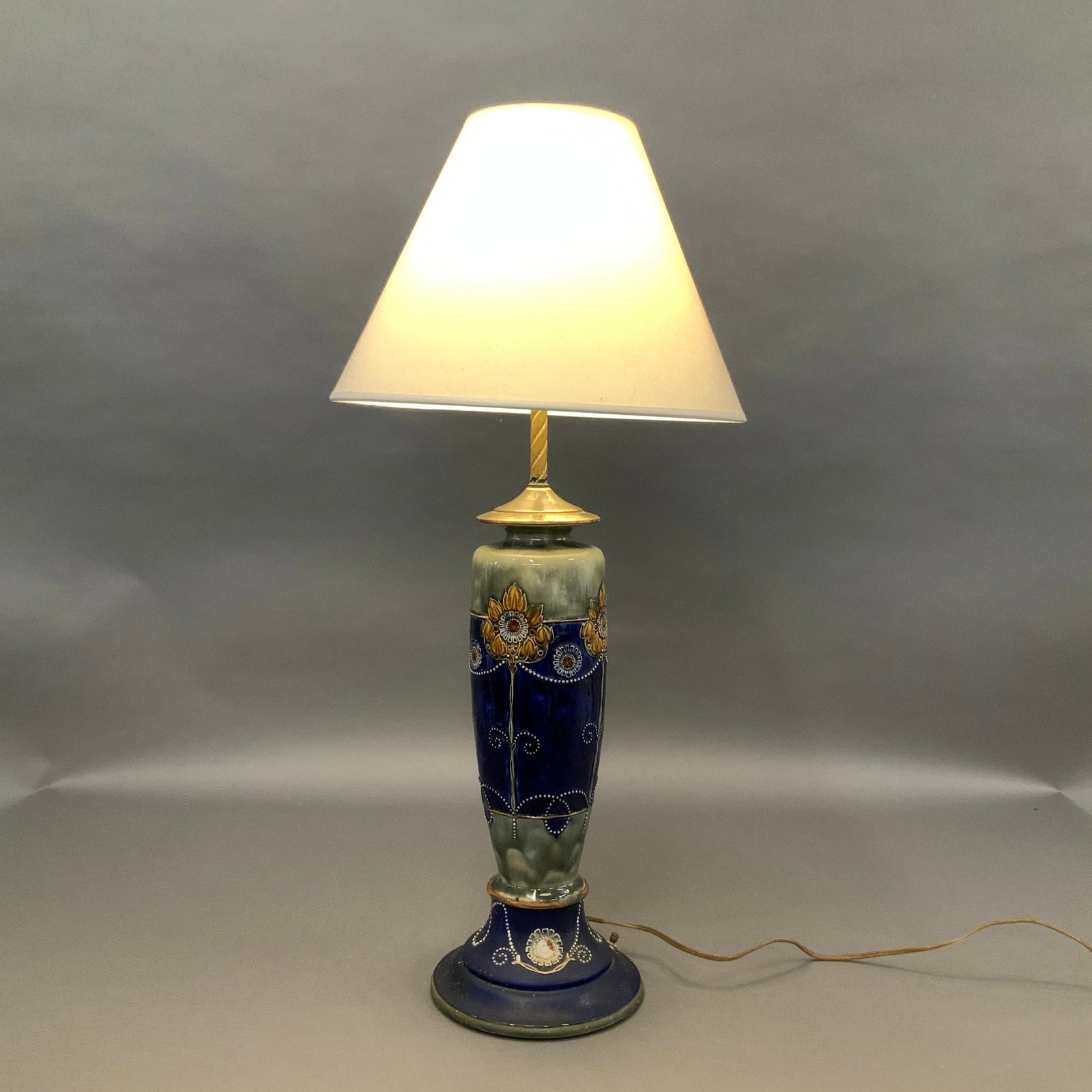 Royal Doulton Lambeth Stoneware Table Lamp with Wooden Base: This Royal Doulton Lambeth stoneware vase lamp features a tapered ceramic body with a gradient glaze transitioning from a pale seafoam green at the top to a deep cobalt blue at the base. The body is d