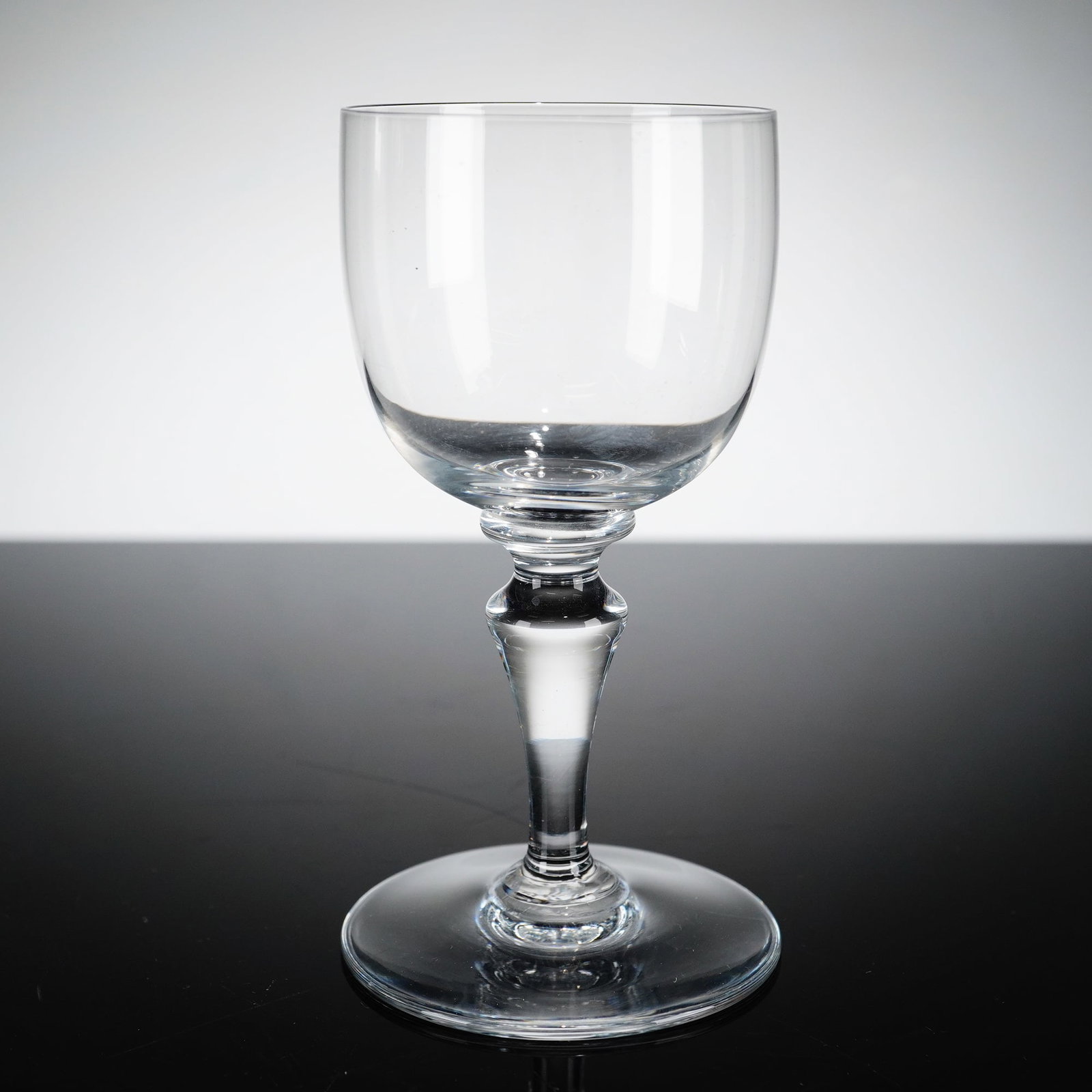 Baccarat Normandie Pattern Crystal Sherry Glass: Baccarat crystal sherry glass in the Normandie pattern. This clear crystal vessel features a plain U-shaped bowl with a slightly flared rim. The stem is designed with multiple knops, including a small