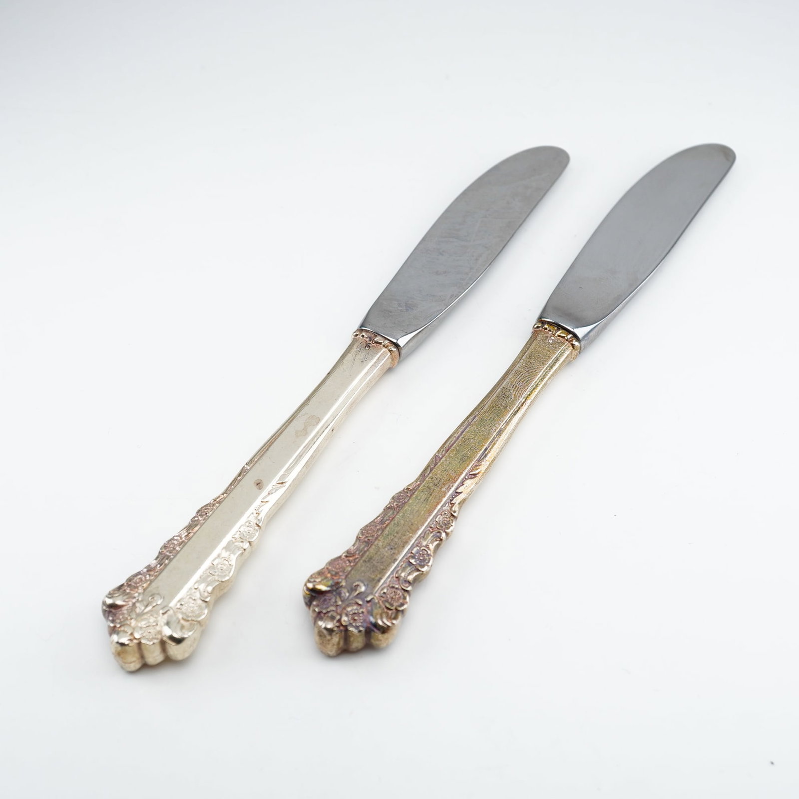 2pc Lunt Sterling Silver and Stainless Steel Butter Spreaders, Belle Meade: Produced by Lunt Silversmiths between 1967 and 1997, this elegant set features finely detailed Rococo-inspired design work with raised floral clusters and scrolling ornamentation along the handle edge