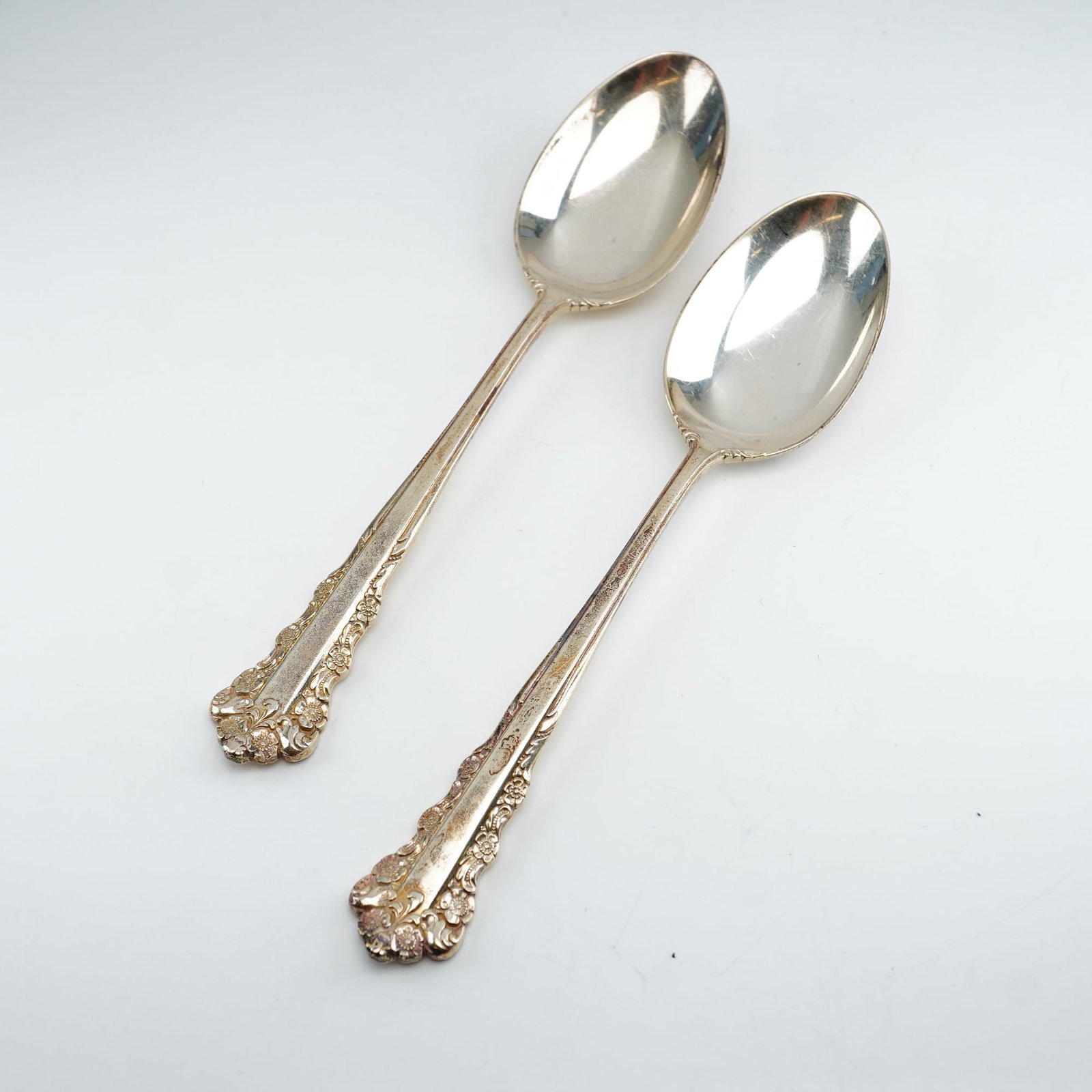 2pc Lunt Sterling Silver Teaspoons, Belle Meade: Two-piece set of Belle Meade Lunt Sterling Silver Teaspoons. Produced by Lunt Silversmiths between 1967 and 1997, with detailed floral relief accents and decorative Rococo-style scrollwork along the h