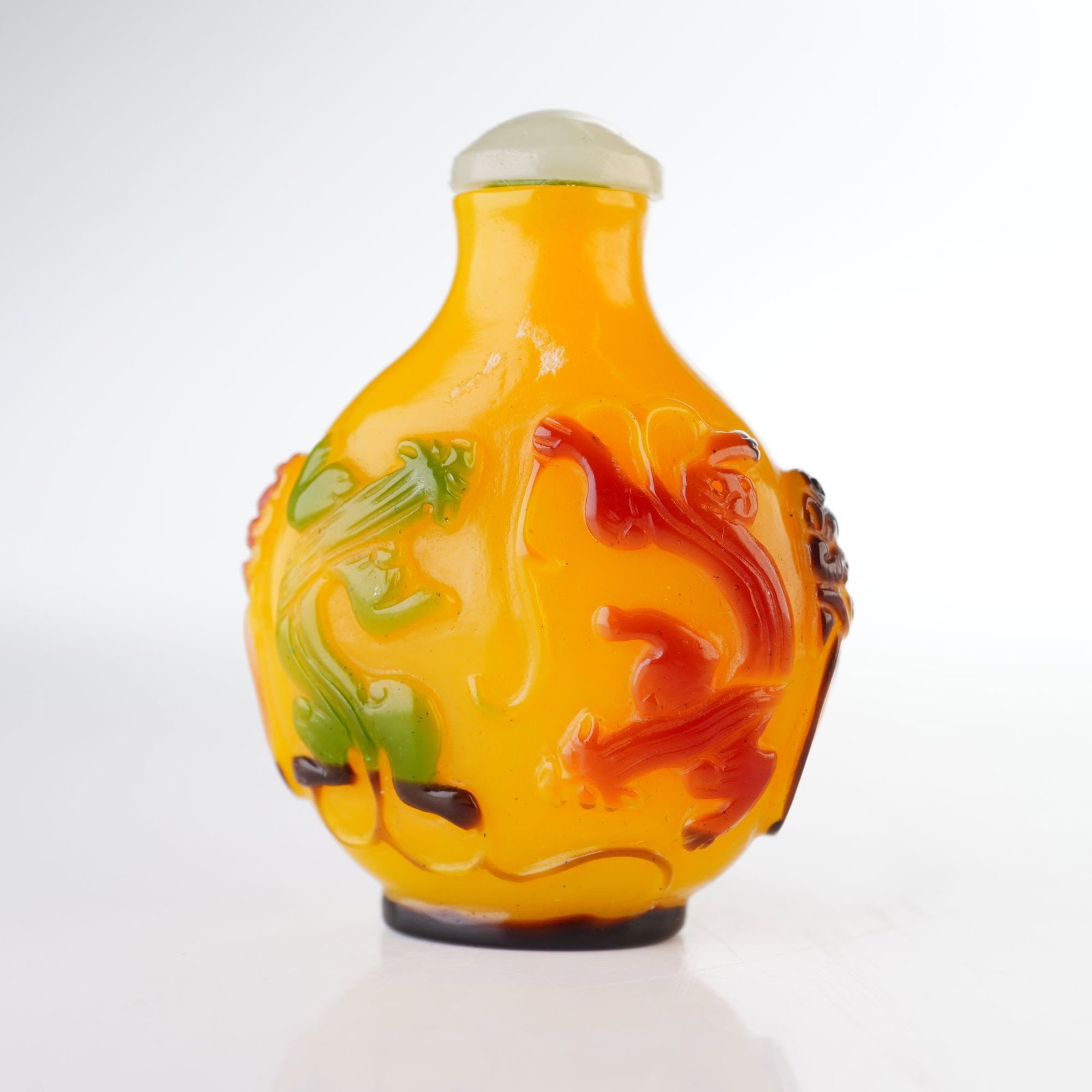 Peking Glass Snuff Bottle, Yellow with Multicolor Overlay, Chilong and Bi: A yellow round snuff bottle decorated with multi-colored high relief figures depicting Chilong and Bi, a dragon passing through a circular form, and various other figures. It is accompanied but a ligh