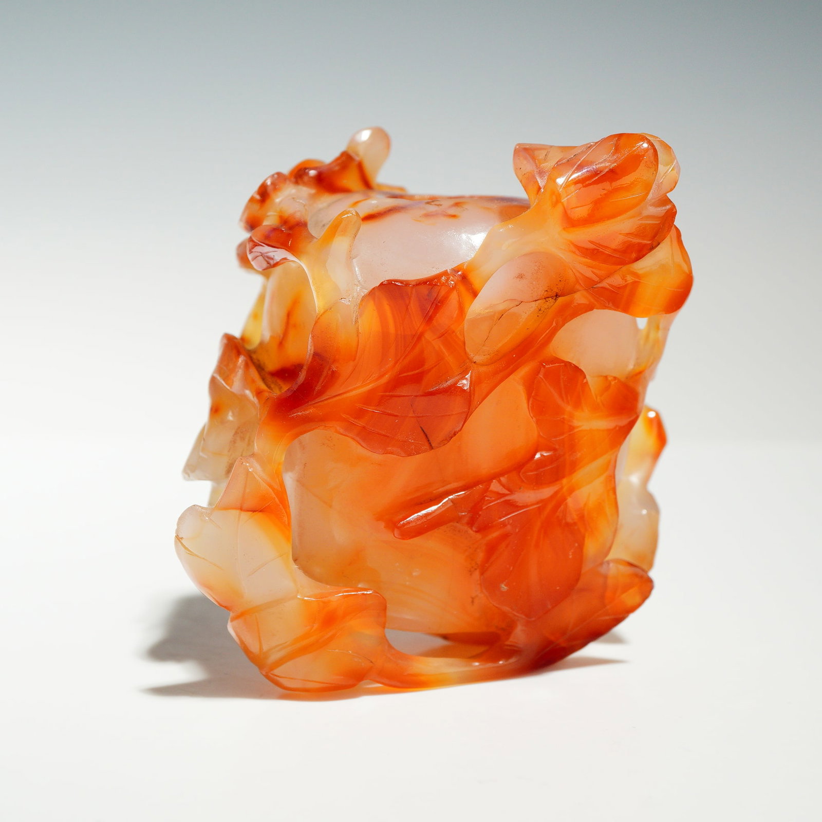 Chinese Carved Carnelian Agate Vase: This lot comprises a Chinese decorative carved carnelian agate vase, likely dating to the late 19th or early 20th century. The vase is carved from translucent carnelian agate with orange-red and milky