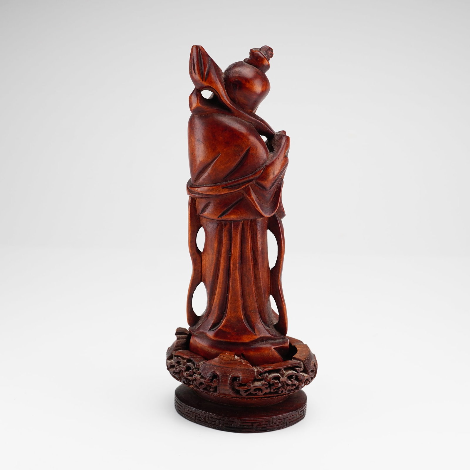 Chinese Carved Hardwood Figure of Shoulao with Intricate Display Base: This lot features a hand-carved hardwood figure of Shoulao, the Chinese Star God of Longevity. The figure is depicted as a smiling elder with a characteristically high cranium, holding a gnarled staff