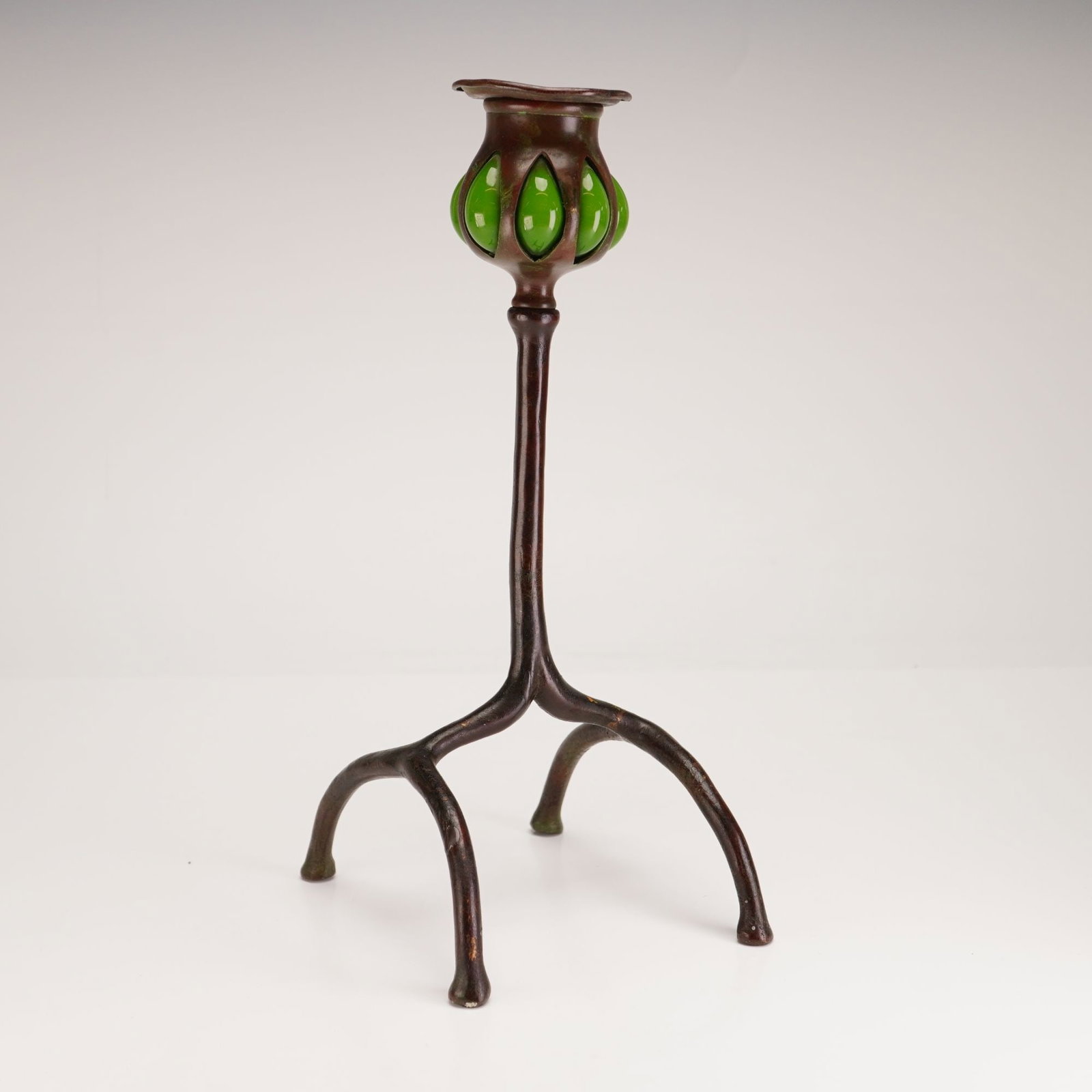 Tiffany Studios Root Candlestick: Tiffany Studios root-form candlestick in patinated bronze, featuring a hand-blown green Favrile glass. The base is stamped Tiffany Studios 1222. Dimensions: 5.00"L x 4.00"W x 10.00"H Weight: 1.00 lb