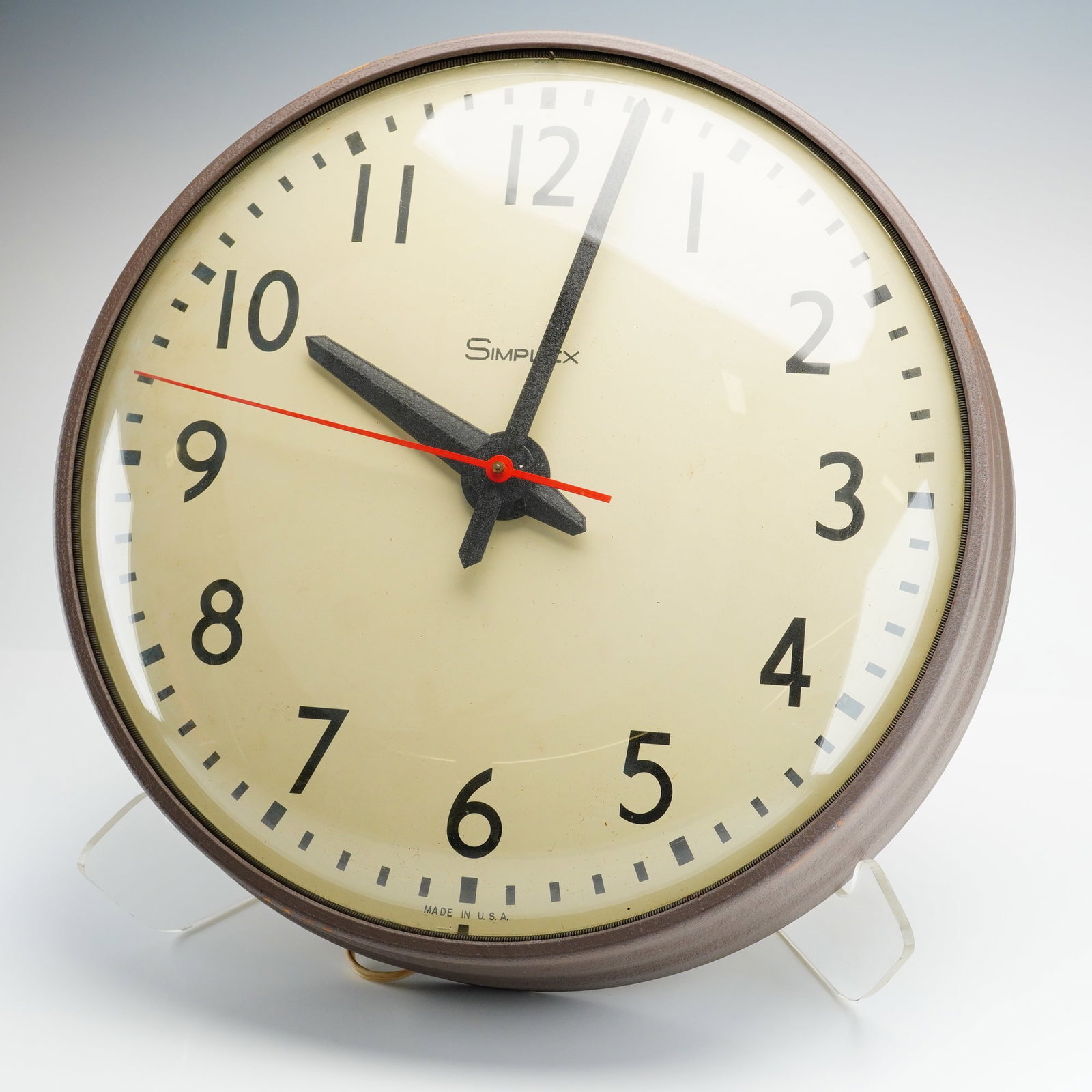 Simplex Industrial Electric Wall Clock: A vintage industrial wall clock manufactured by the Simplex Time Recorder Co. of Gardner, Massachusetts. The timepiece features a circular metal case with a dark brown textured finish and a convex gla