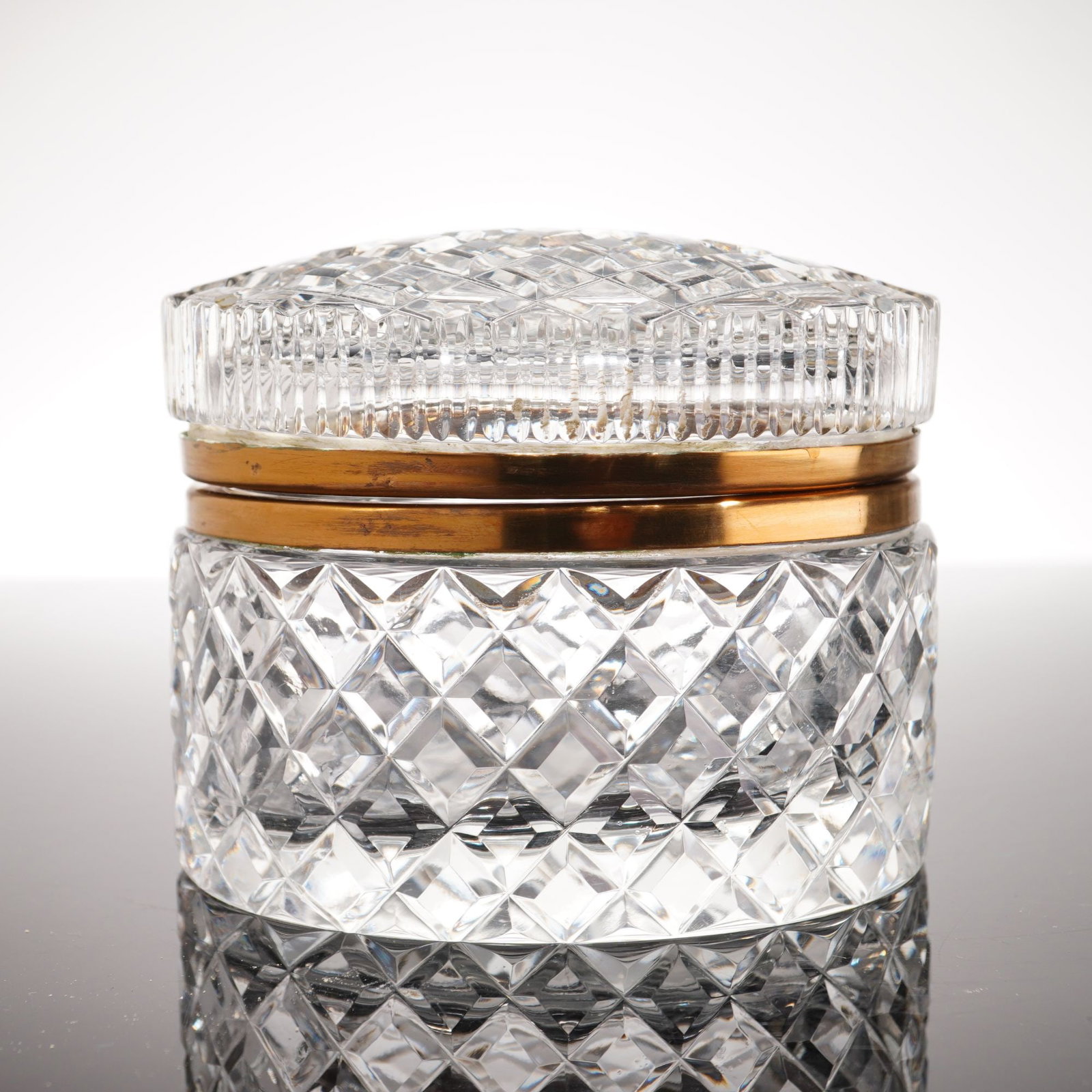 Mid-Century French Style Cut Crystal Oval Casket Box: This is an oval-shaped jewelry casket box crafted from heavy, clear cut crystal. The body and the center of the domed lid are decorated with a deep diamond-cut pattern. The perimeter of the lid featur