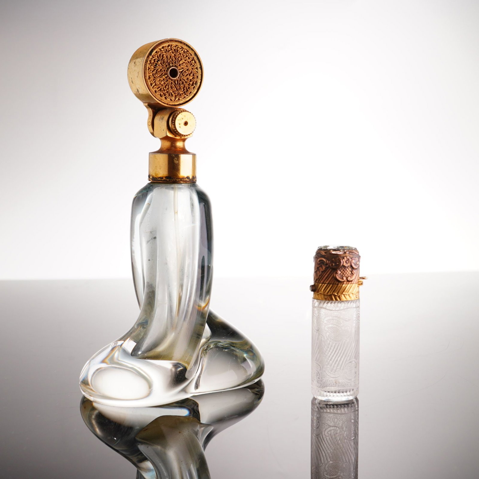 2pc Glass Perfume Bottles including a Marcel Franck Escale Atomizer: This lot comprises two vintage glass perfume containers, including a dresser-top atomizer and a travel bottle. The larger piece is a French art glass atomizer by Marcel Franck. The clear glass body is