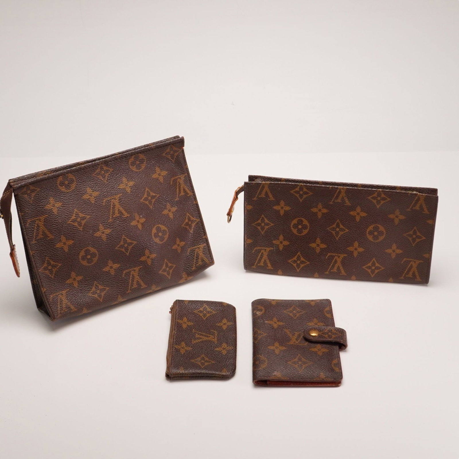4pc Louis Vuitton Monogram Coated Canvas Accessory and Toiletry Pouch Group: This set of accessories is crafted from signature Louis Vuitton Monogram coated canvas and features gold-tone brass hardware. The group consists of a large toiletry pouch, a flat rectangular zippered 