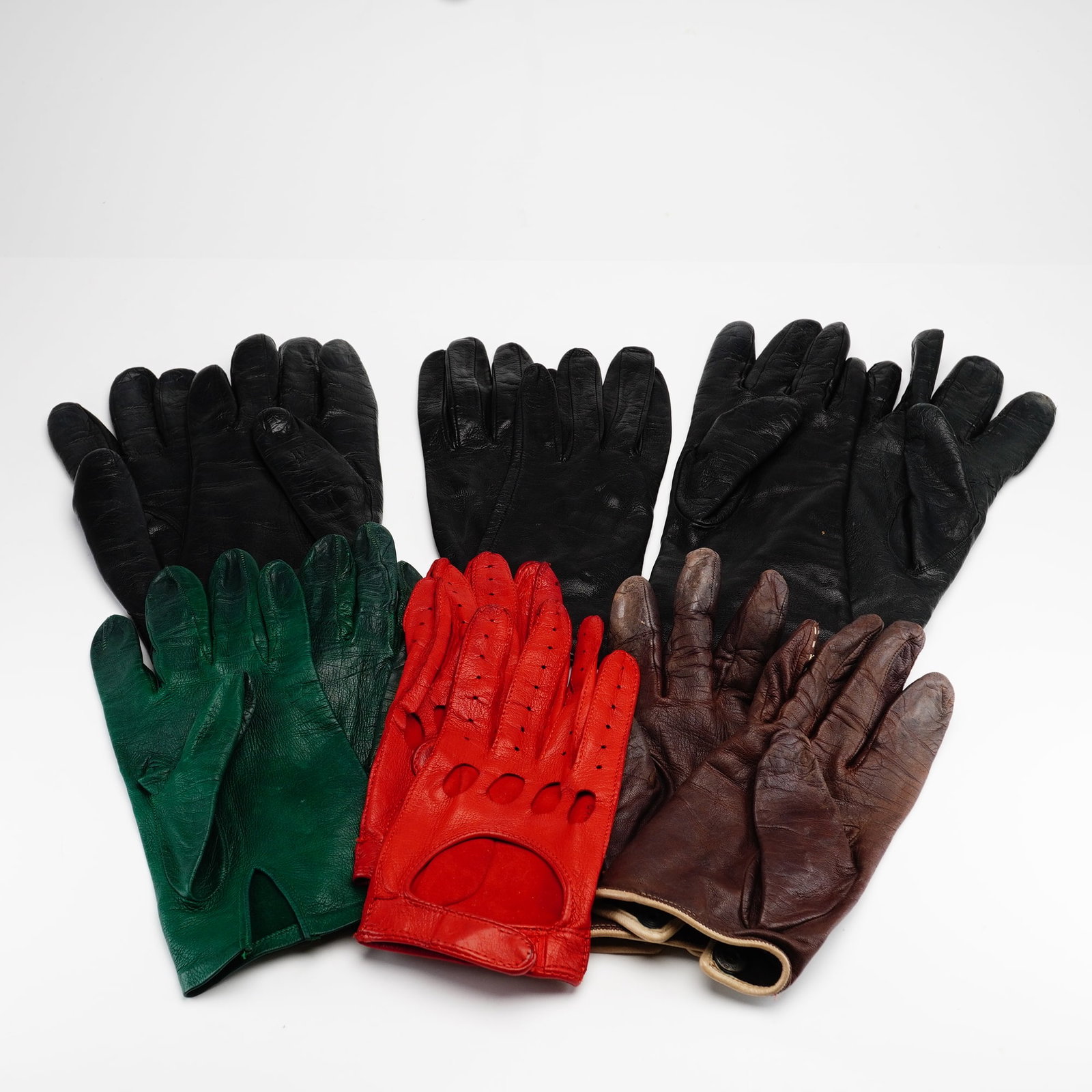 Six Pairs of Ladies Genuine Leather Gloves: This collection consists of six pairs of ladies small sized leather gloves in various colors and styles. The assortment includes three pairs of black leather gloves, featuring one pair with elongated