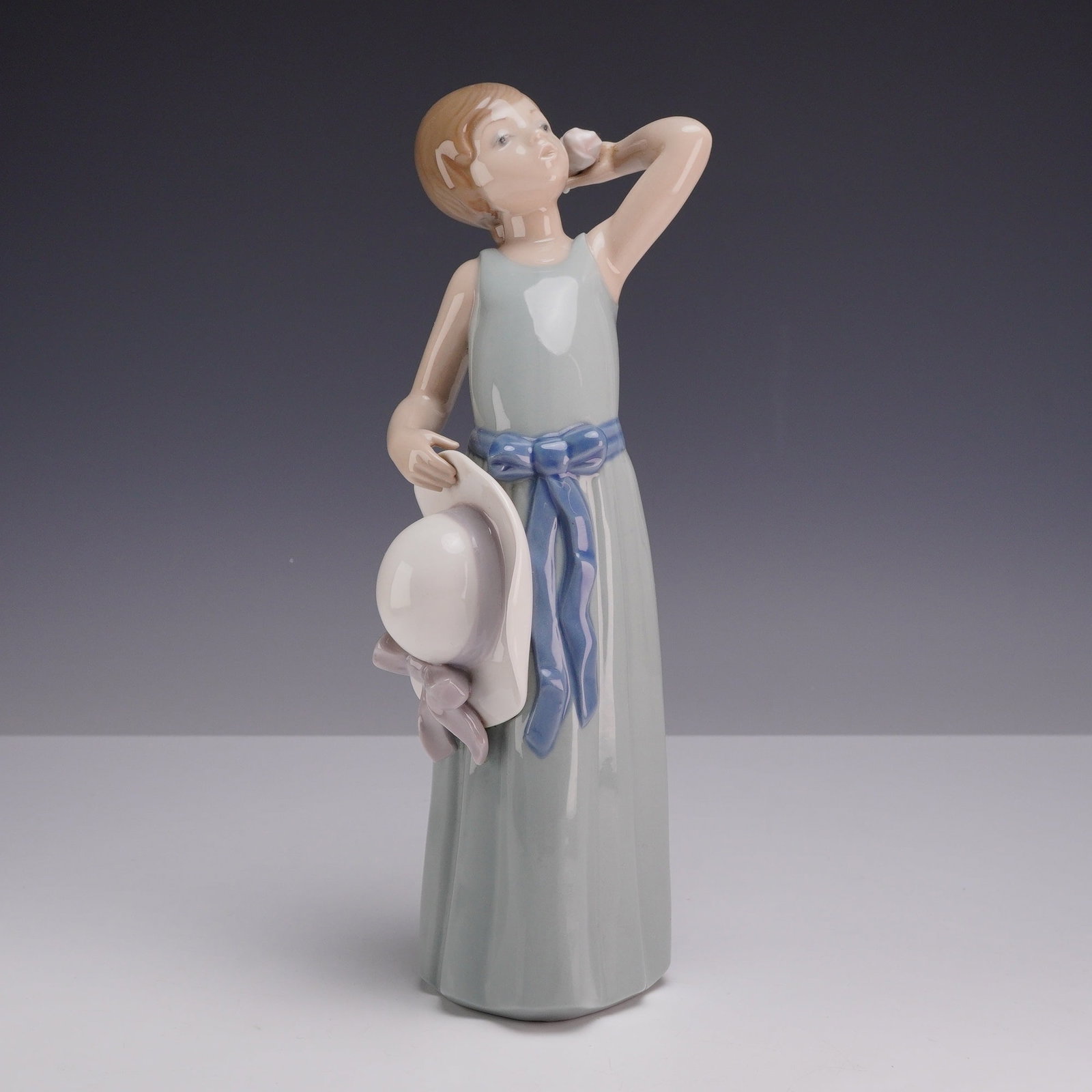 Lladro Porcelain Figurine Model 5010 Prissy Girl with Hat and Rose: A glazed porcelain figurine produced by the Spanish manufacturer Lladro, model number 5010, titled Prissy. Designed by sculptor Francisco Catala and first issued in 1978, the figurine depicts a young 
